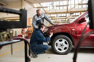 Mechanics checking damaged automobile — Paggen's Auto Body & Sandblasting, LLC in St. Stephen, MN