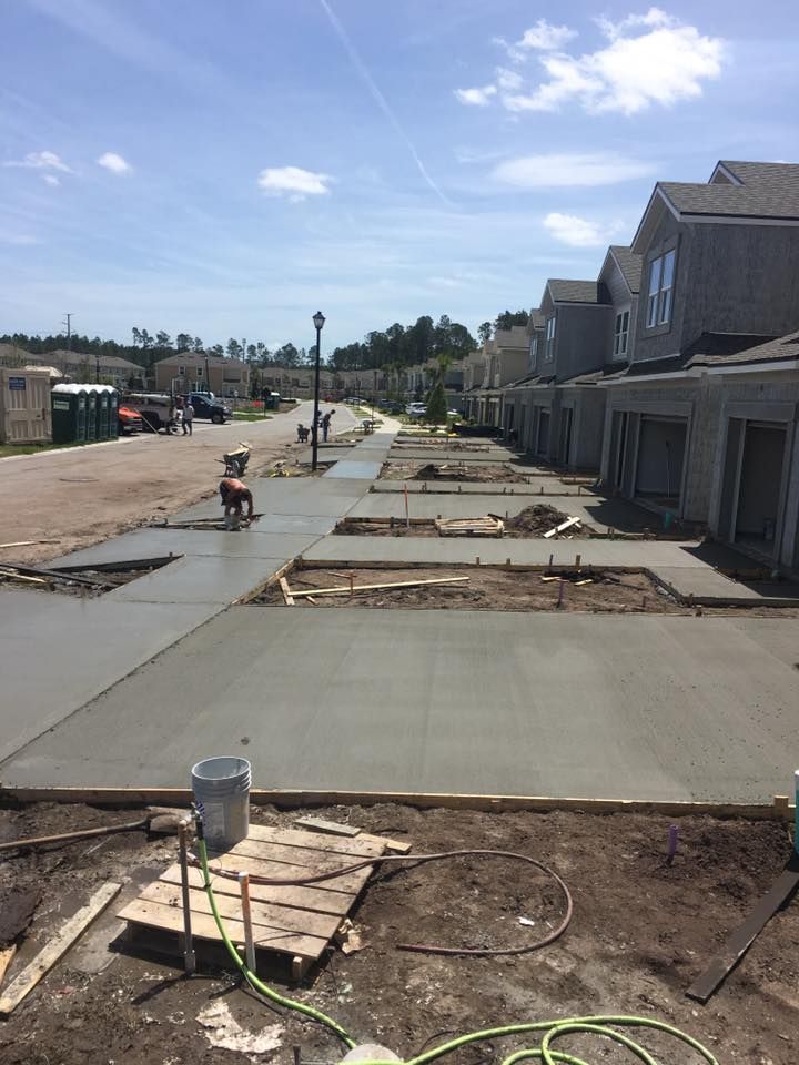 A concrete sidewalk is being built in front of a row of houses.