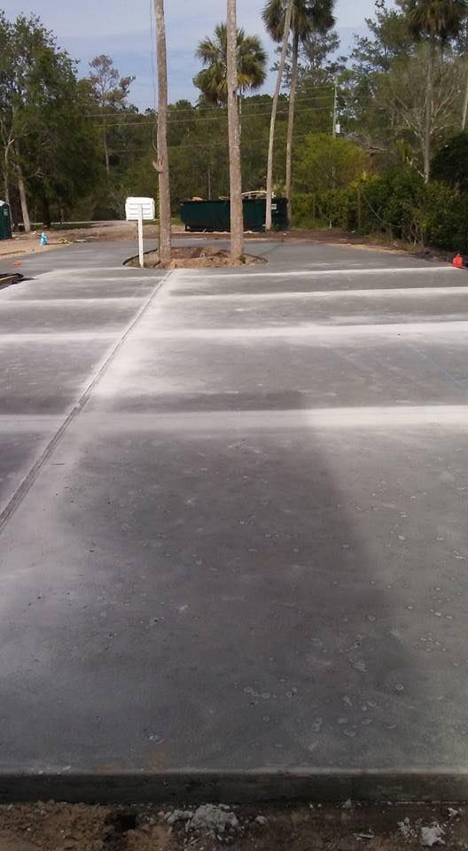 A concrete parking lot with palm trees in the background.