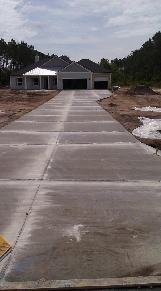 A concrete driveway leading to a house under construction.