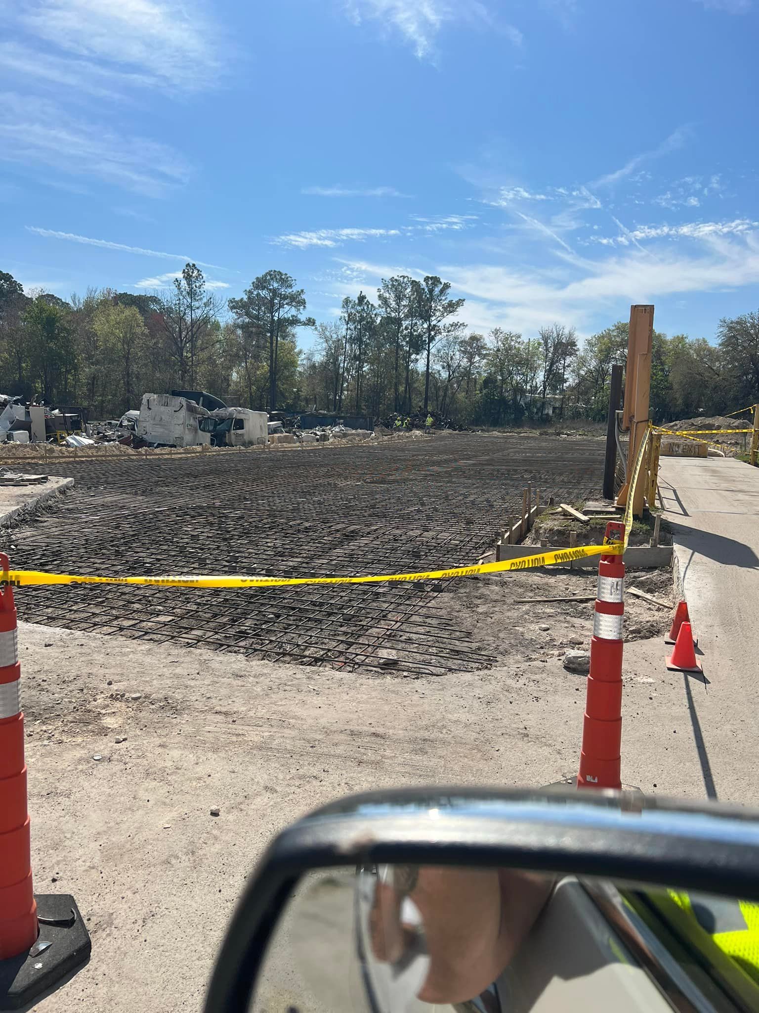 A person is looking at a construction site in their rear view mirror.