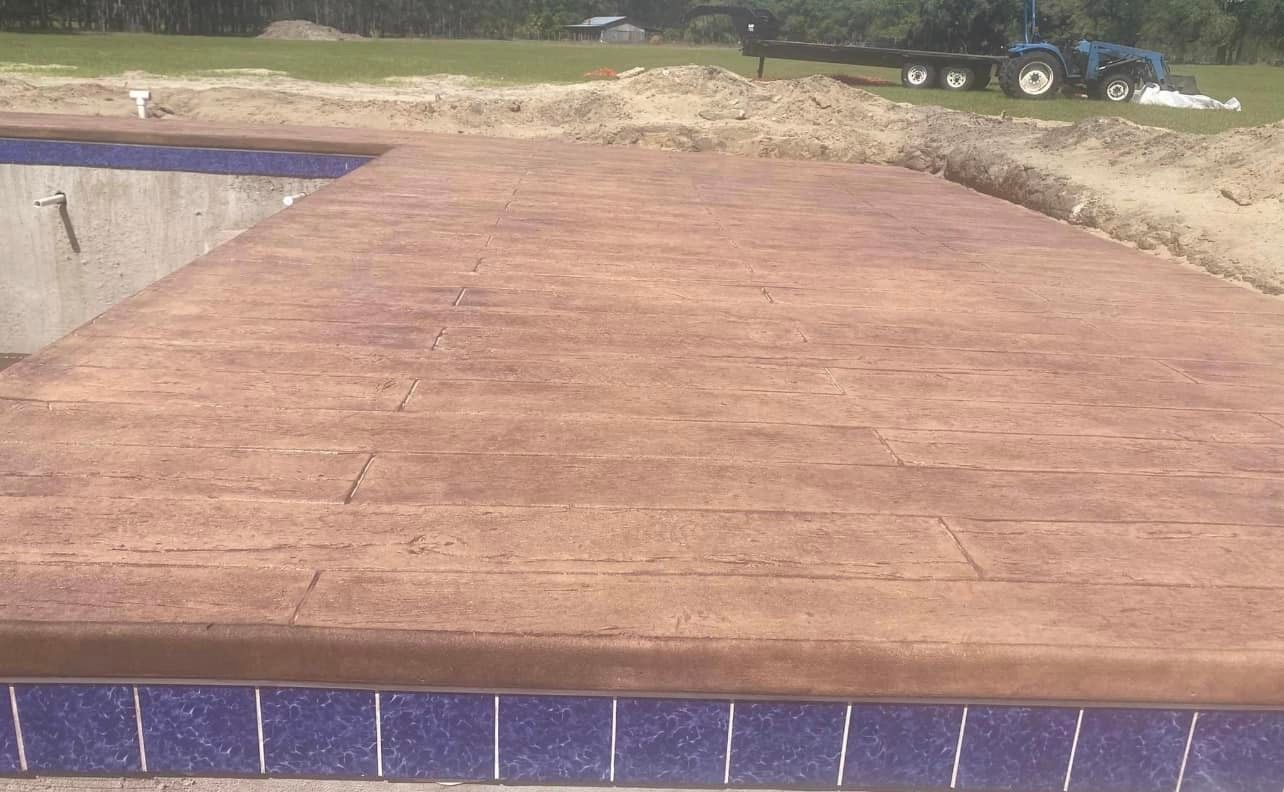 A concrete walkway is being built next to a swimming pool.