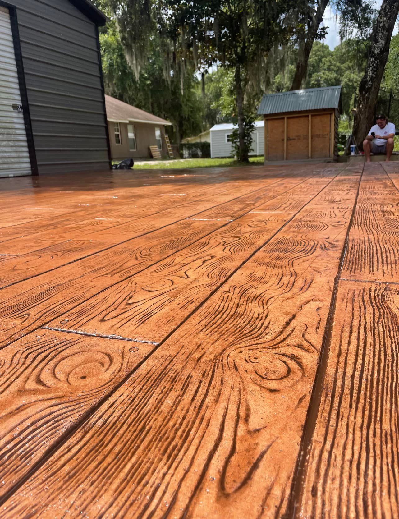 A man is sitting on a wooden deck in front of a garage.