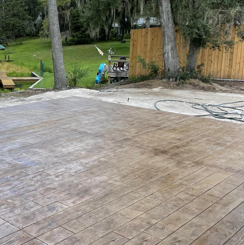 A concrete patio with a wooden floor and a wooden fence in the background.