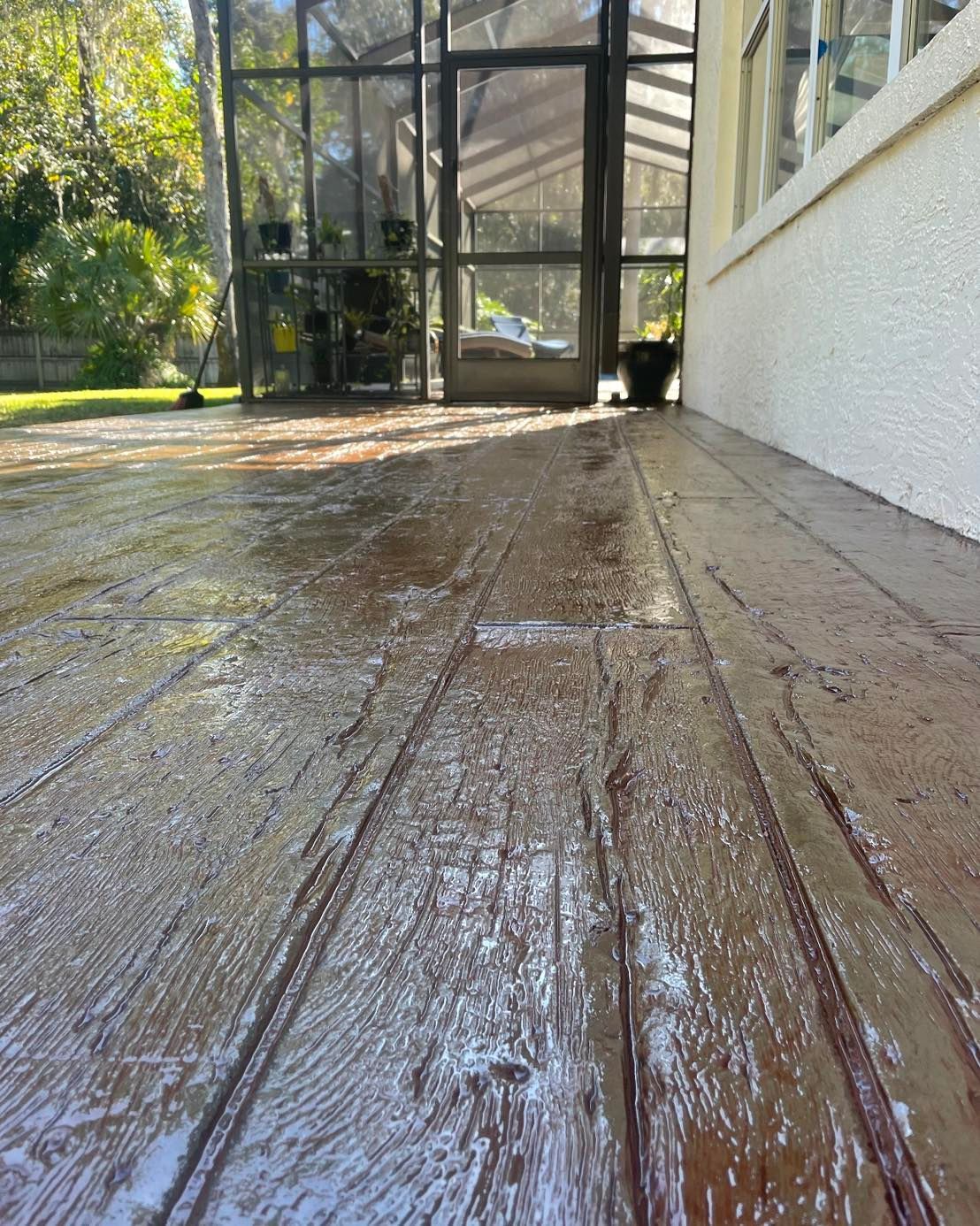 A wooden deck with a screened in porch in the background.