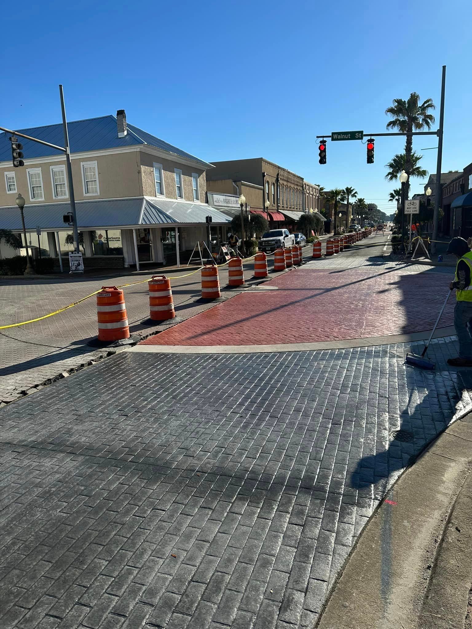 A man in a yellow vest is standing in the middle of a street.