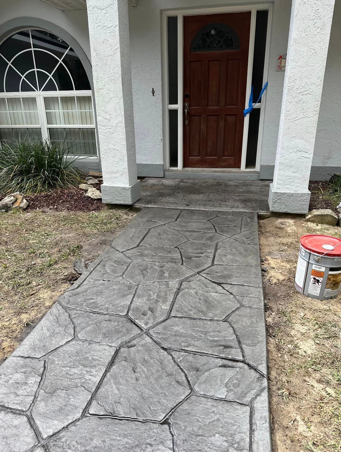 A concrete walkway leading to the front door of a house.