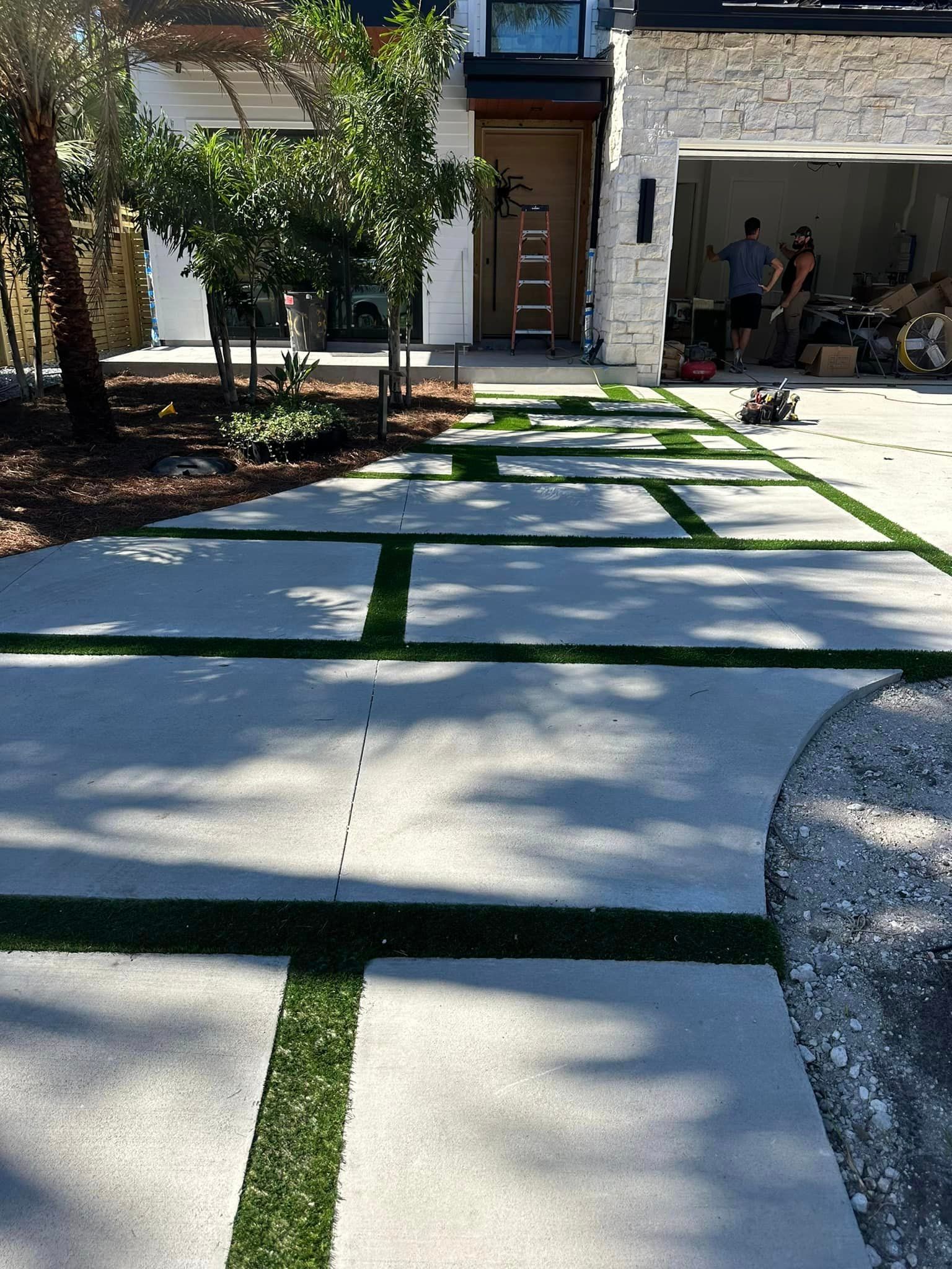 A concrete walkway with grass on the side of it in front of a house.