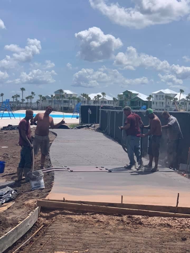 A group of construction workers are working on a concrete walkway.