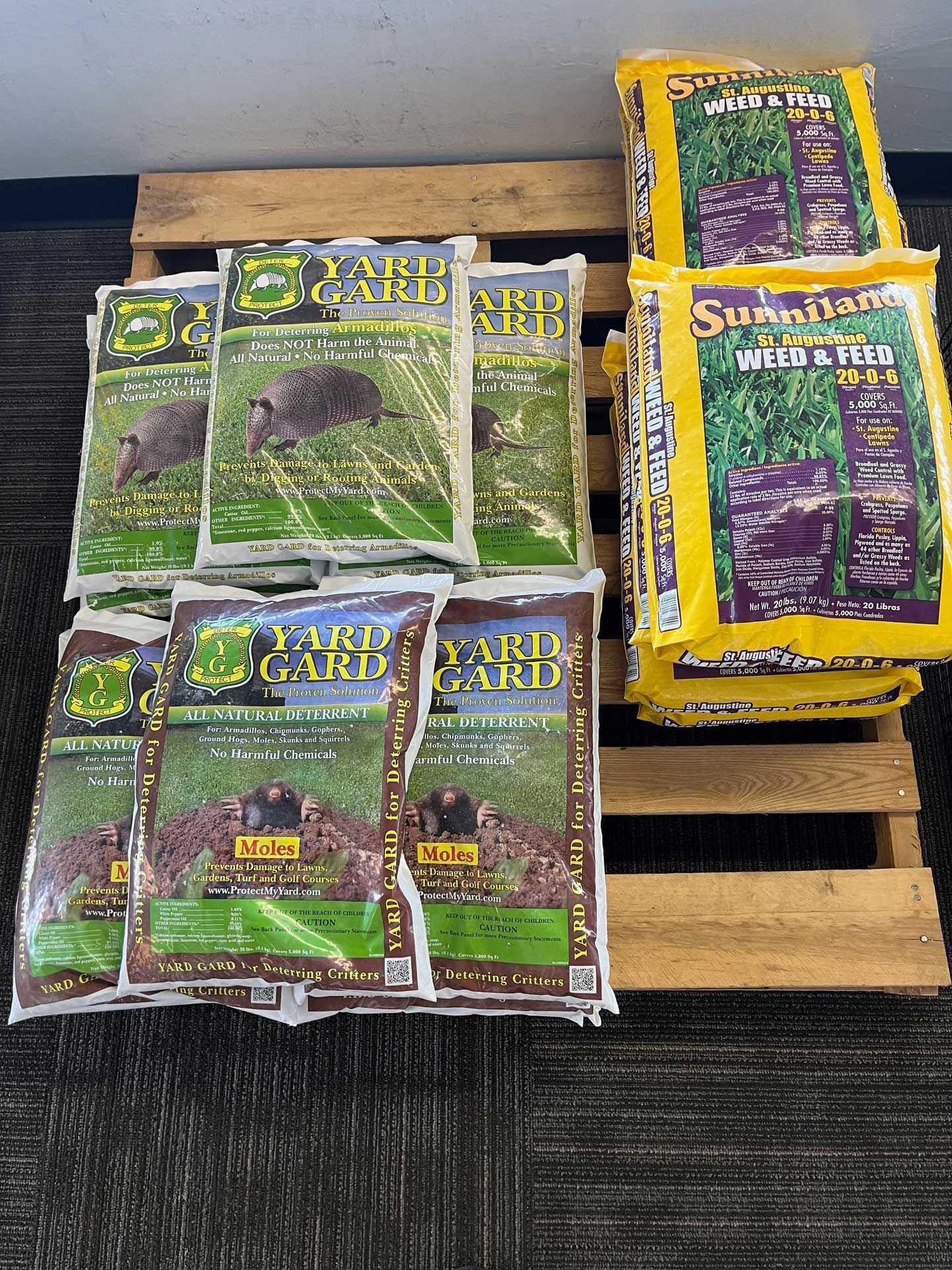 A bunch of bags of lawn fertilizer are sitting on a wooden pallet.