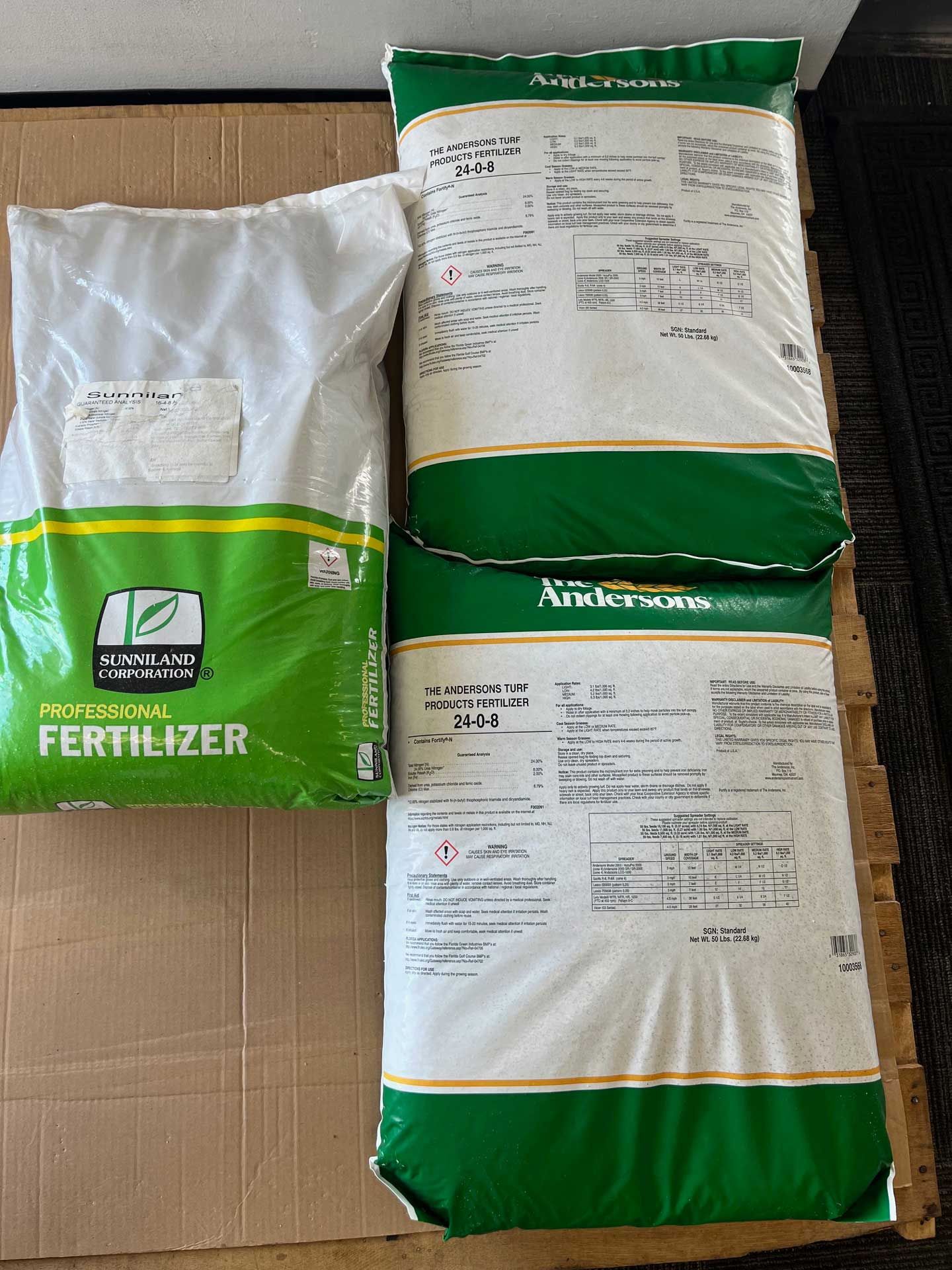 Two bags of fertilizer are sitting on top of a cardboard box.