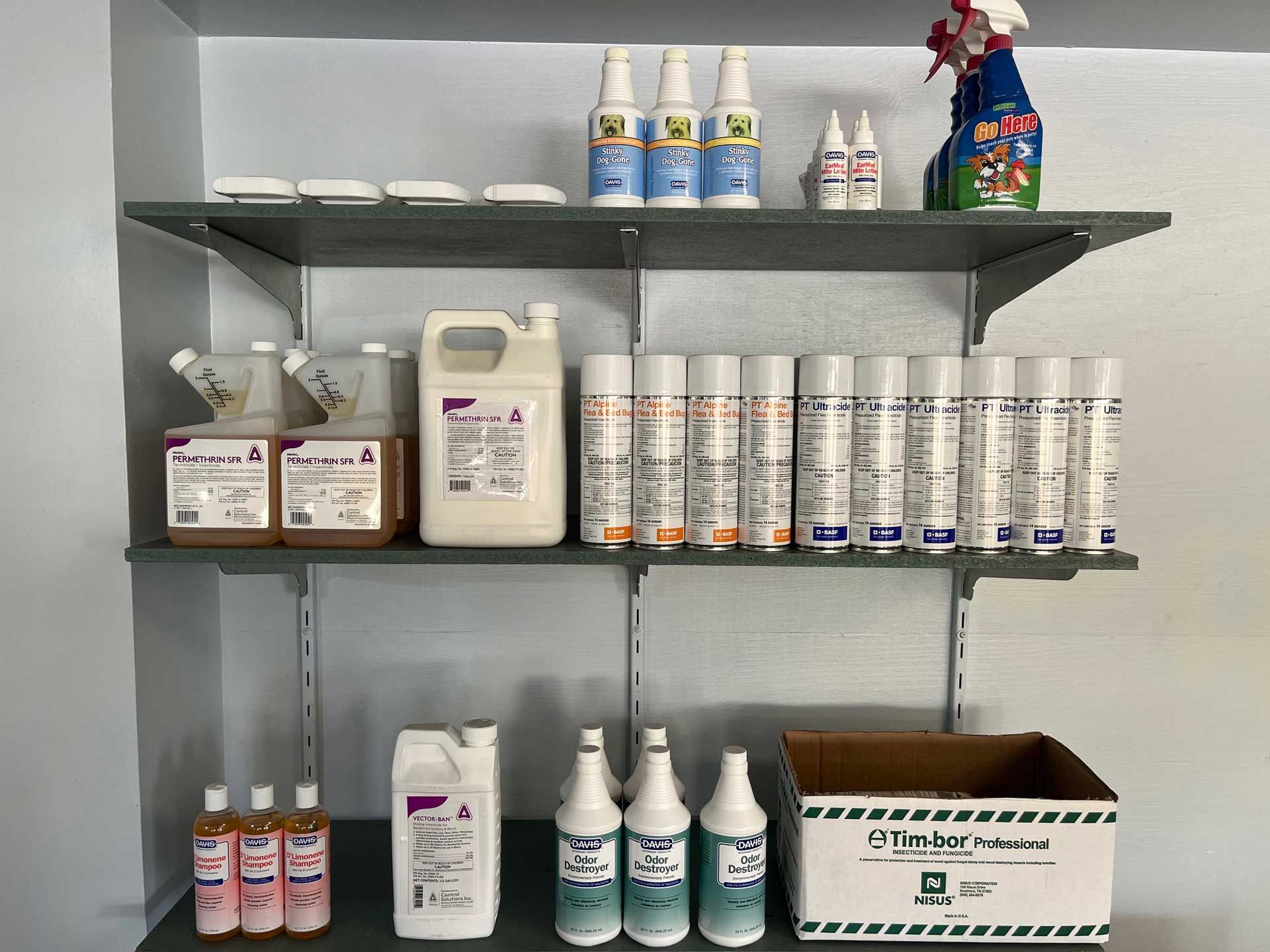 A shelf filled with bottles and spray bottles of cleaning products.