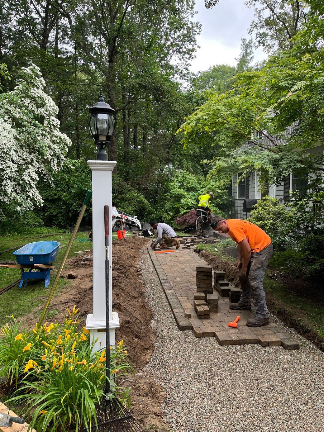 A group of people are working on a gravel driveway.