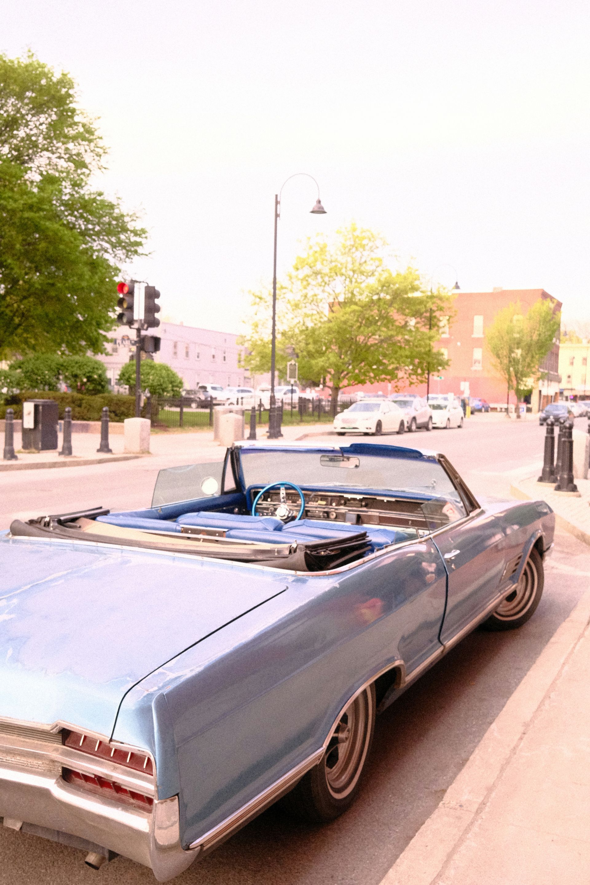 A blue convertible is parked on the side of the road
