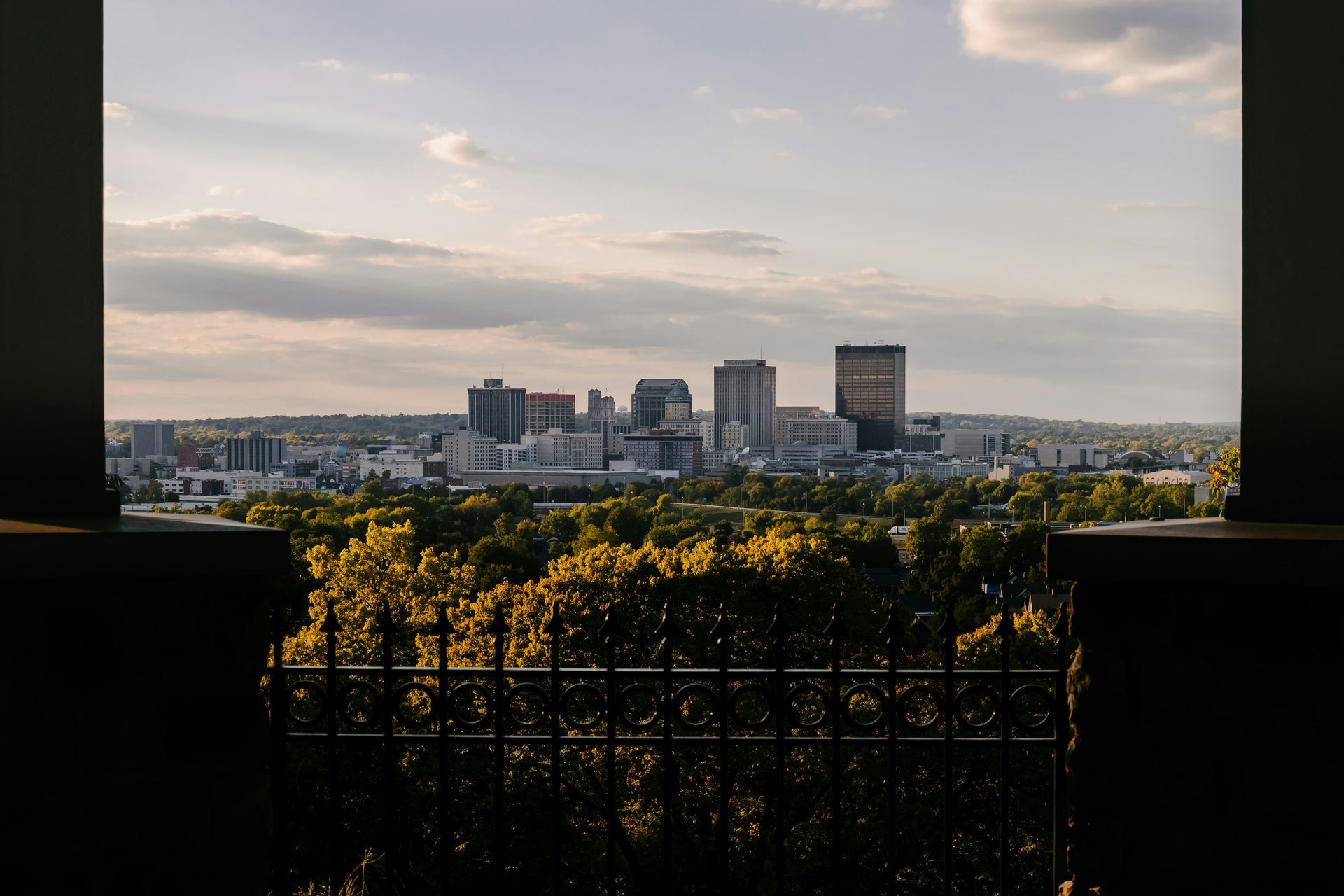 A view of a city from a balcony with trees in the foreground