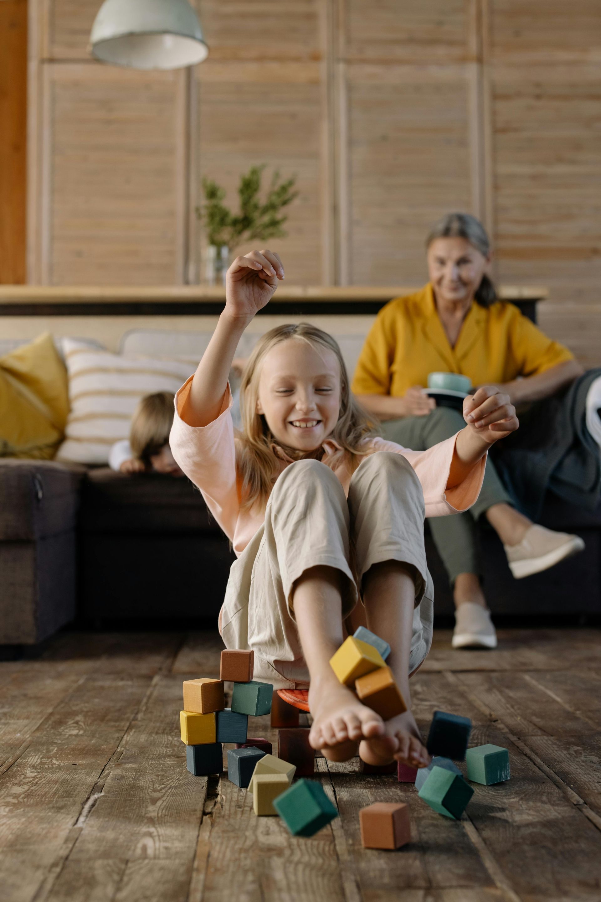 A little girl is sitting on the floor playing with wooden blocks.
