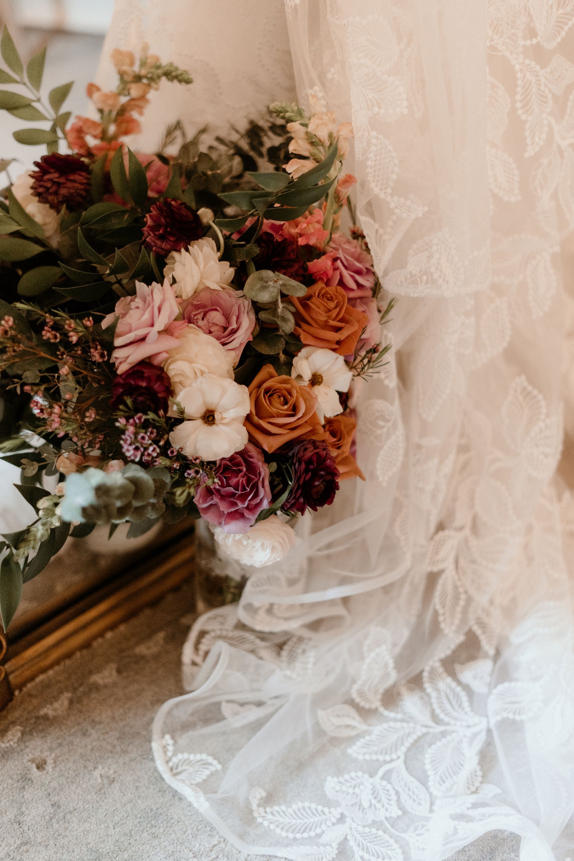 A bouquet of flowers is sitting on top of a bride 's wedding dress.