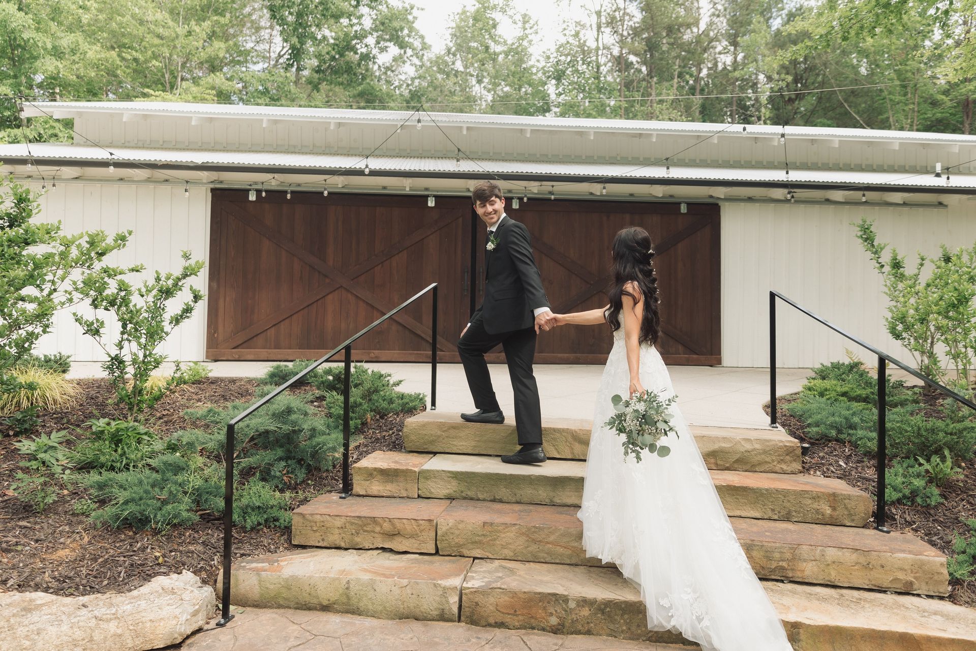 A bride and groom are walking down a set of stairs holding hands.