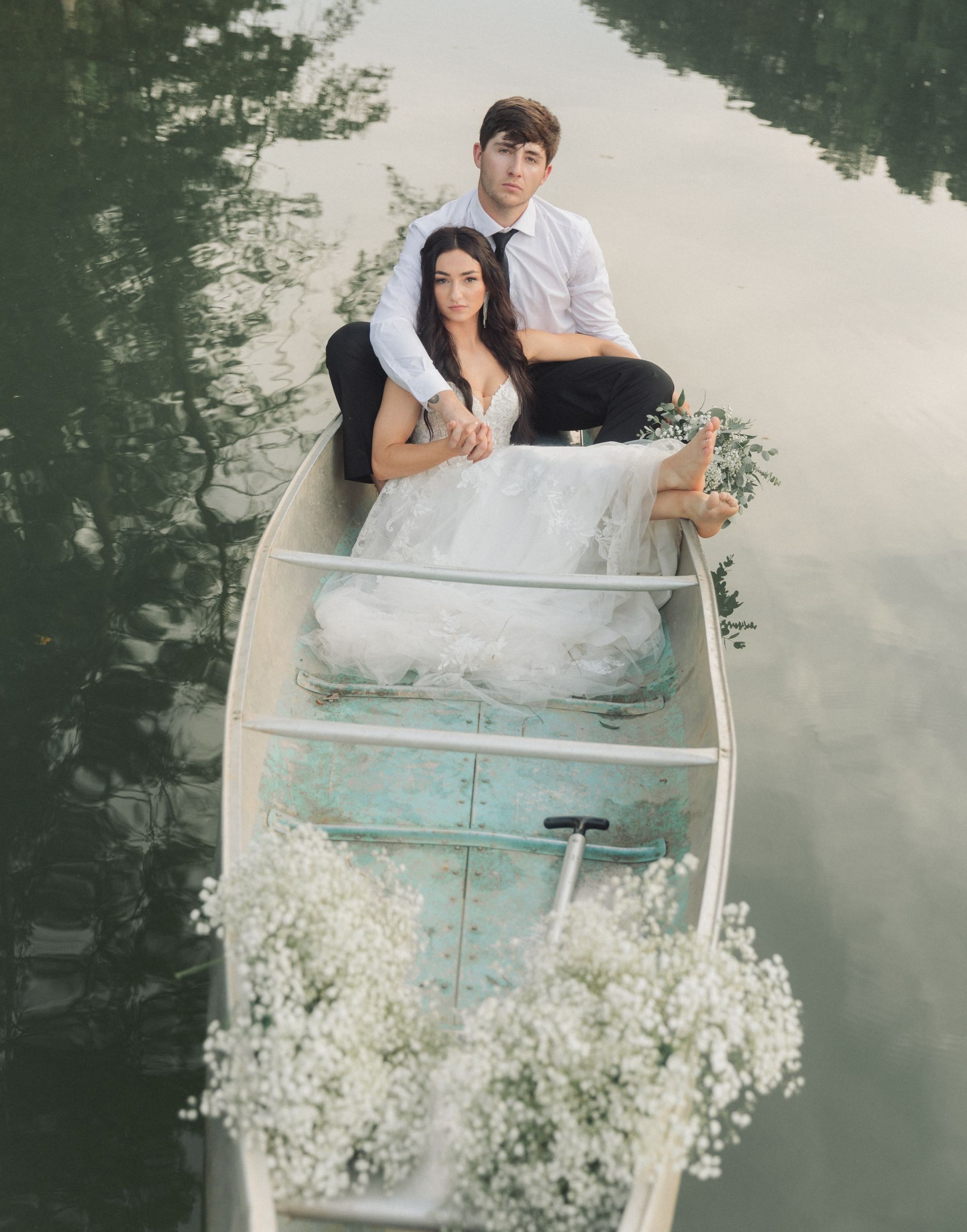 A bride and groom are sitting in a boat on a lake.
