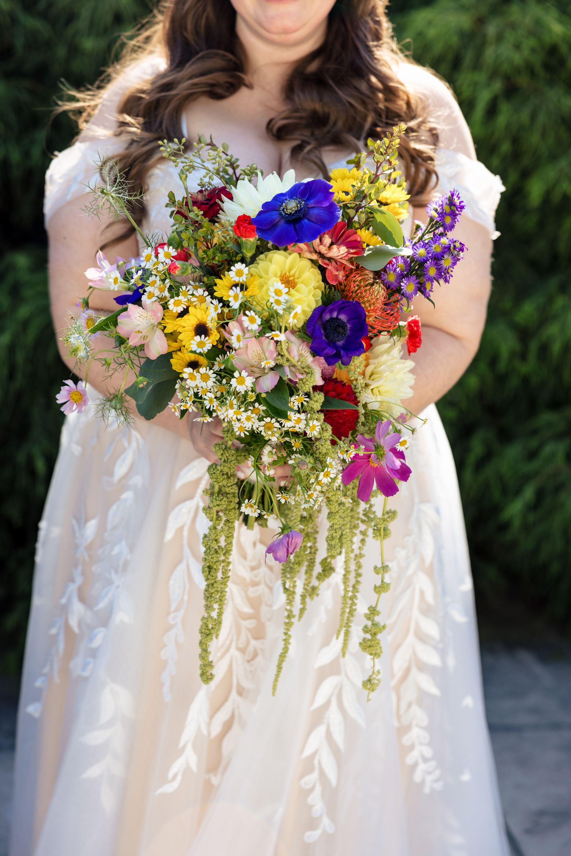 A bride in a white dress is holding a colorful bouquet of flowers.