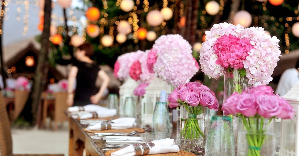 A long table with pink flowers in vases on it.