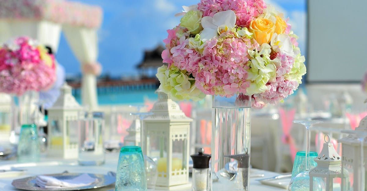 A table set for a wedding reception with flowers in vases on it.