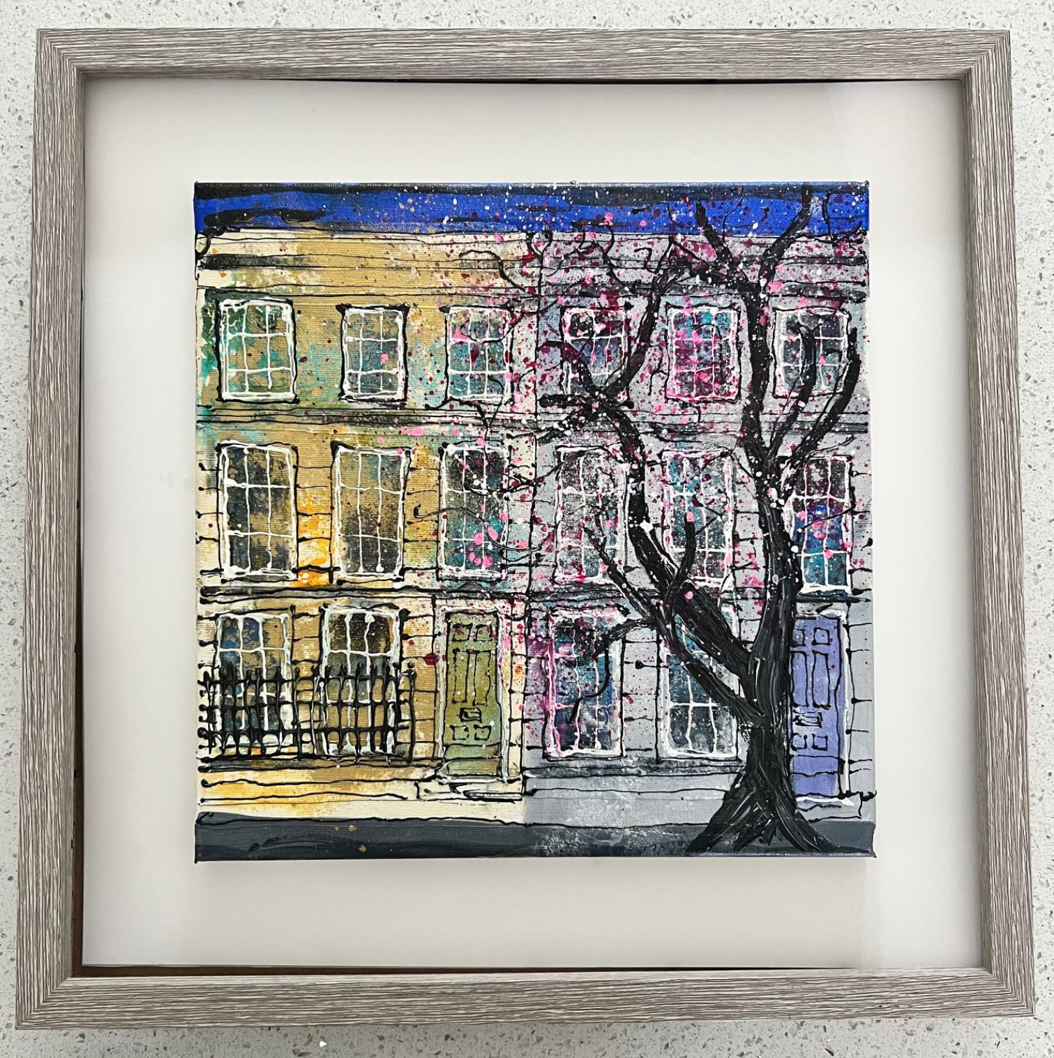 Square painting of a building with a tree in front. Yellow/purple building, black tree, white details, in a gray frame.