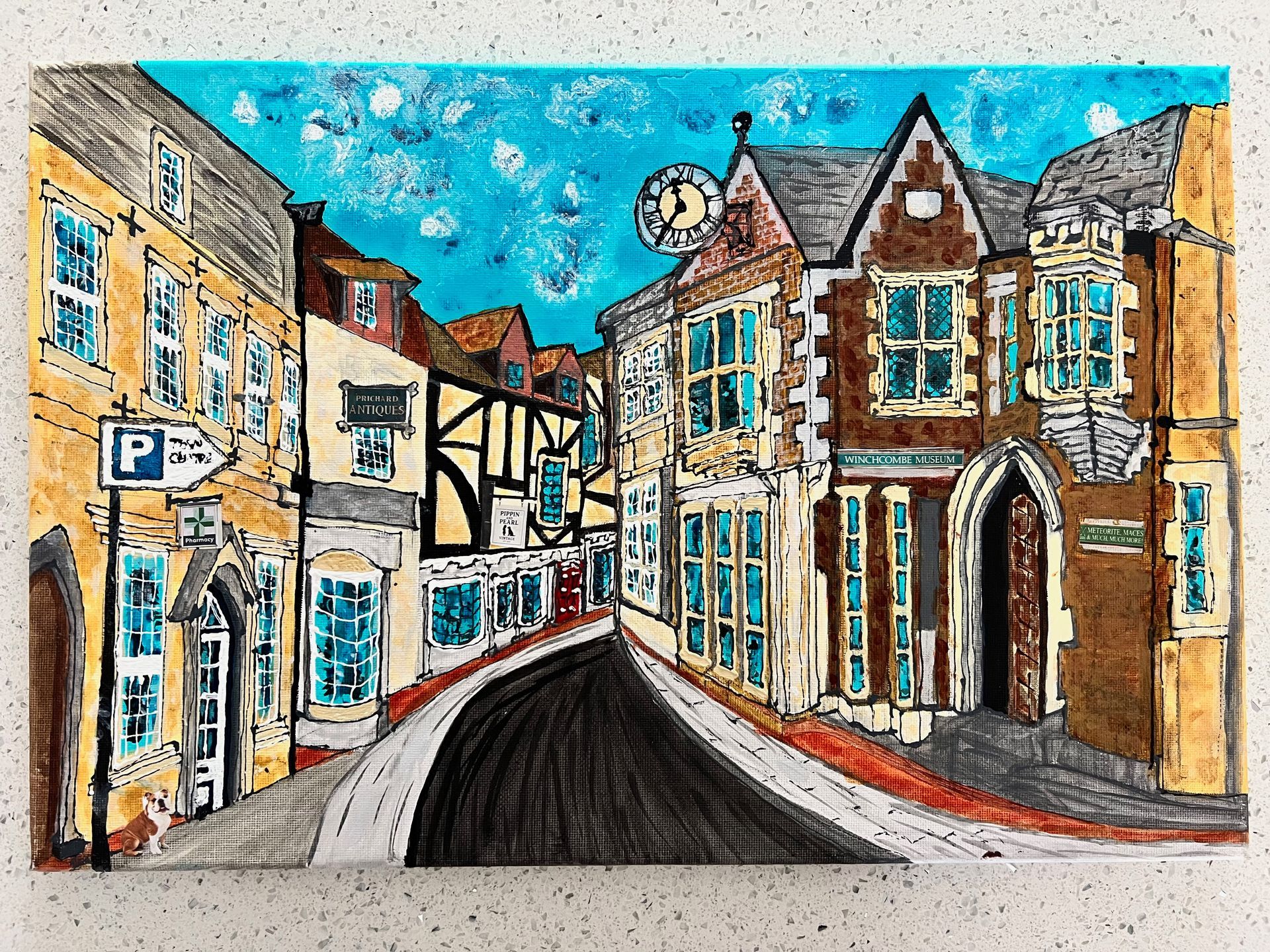 Street scene with buildings; perspective of road; clock tower, varying architecture. Blue sky, brown, yellow hues.