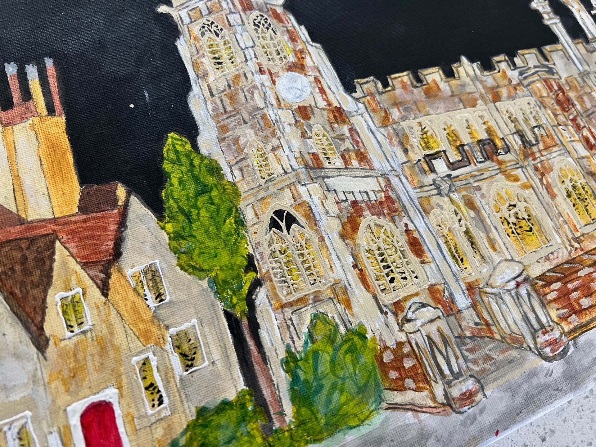 Watercolor painting of a church tower and buildings, set against a dark background, in warm hues.