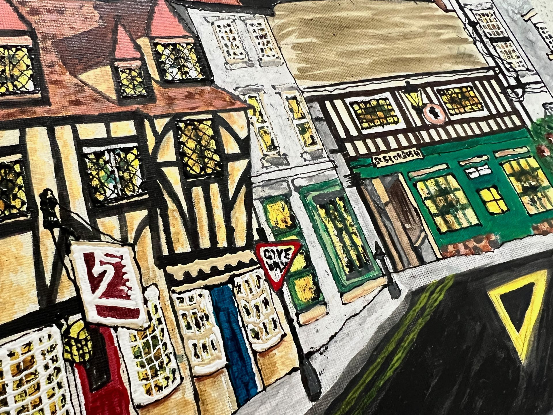 Colorful illustration of a street scene featuring Tudor-style buildings, shop fronts, and road signs.