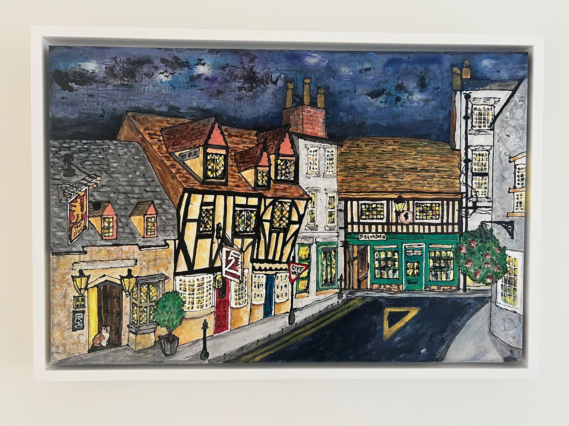 Colorful illustration of a street scene featuring Tudor-style buildings, shop fronts, and road signs.