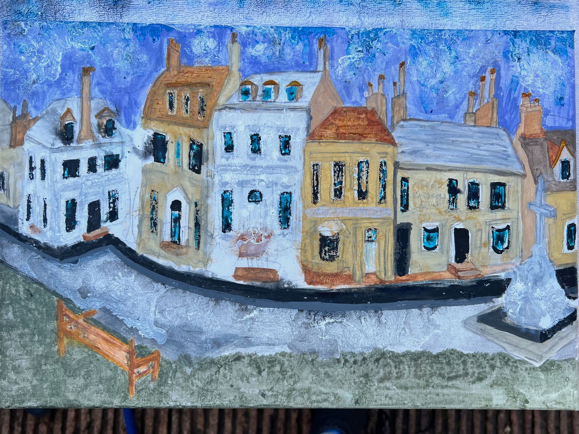 Townhouses with varying colors, street, and bench under a blue sky.
