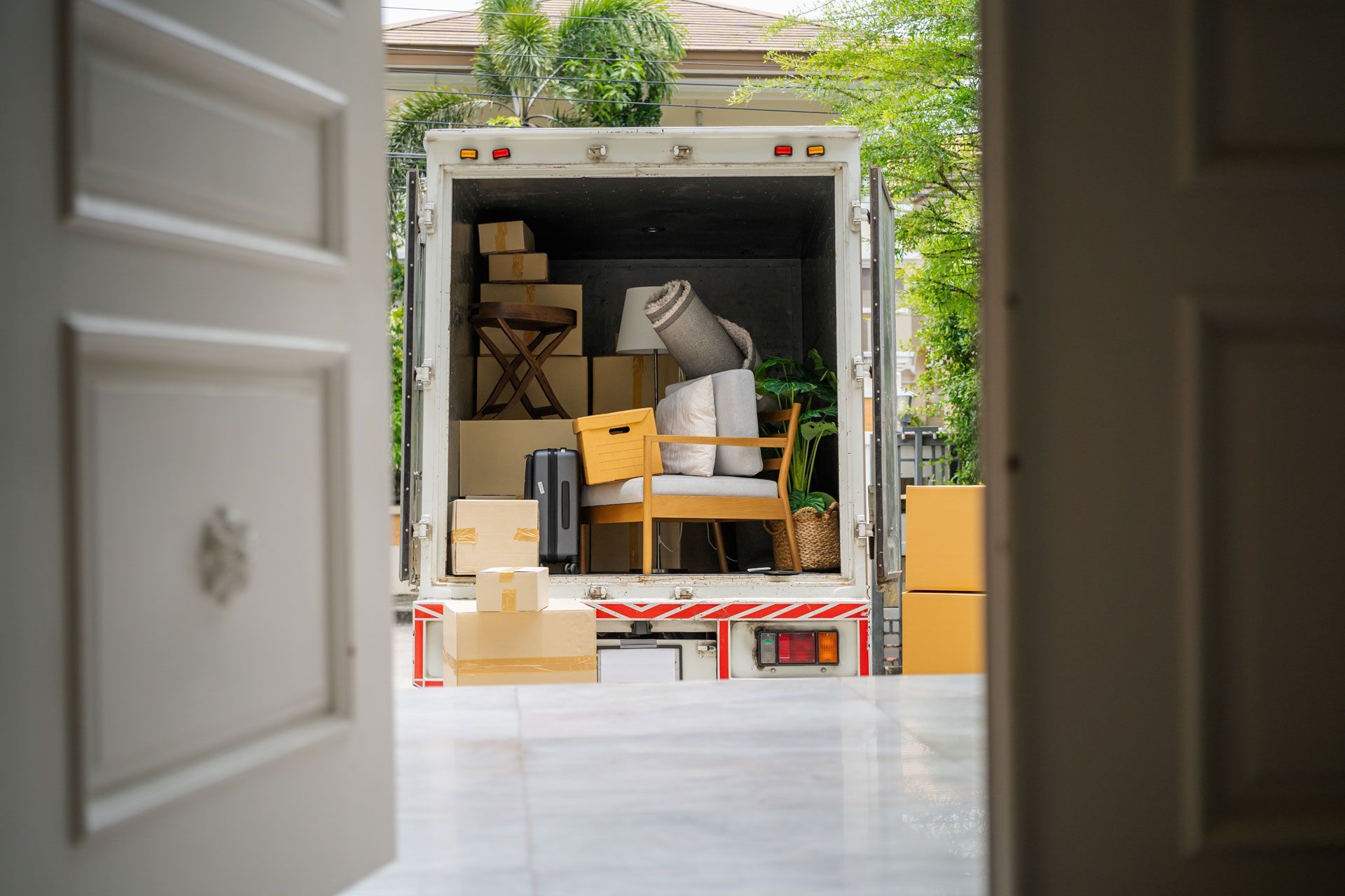 Moving truck loaded with boxes and furniture, seen from an open doorway.