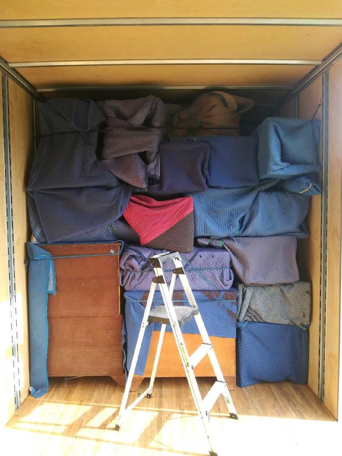 A ladder is sitting in a room filled with blankets and boxes