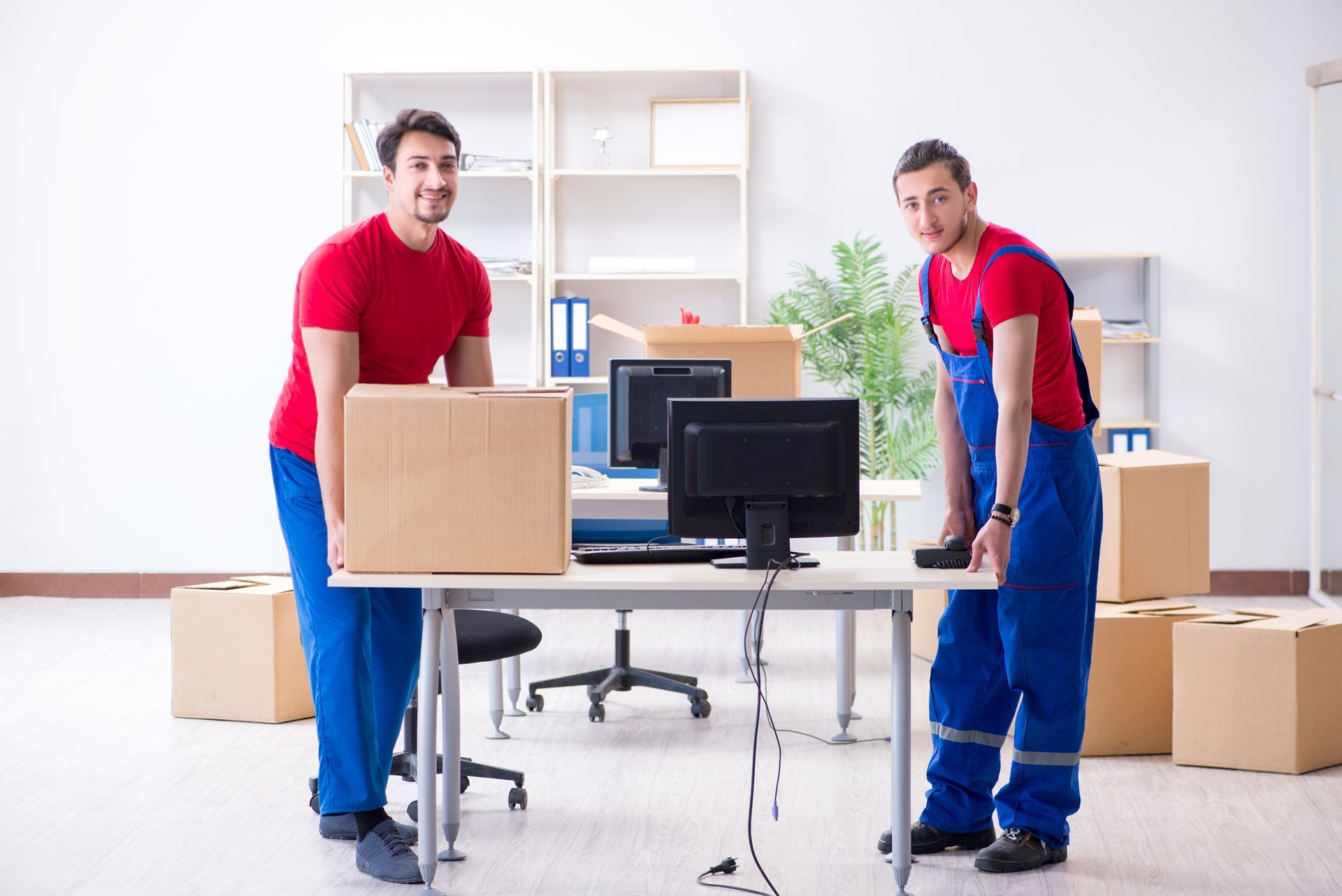 Two men are carrying boxes in an office
