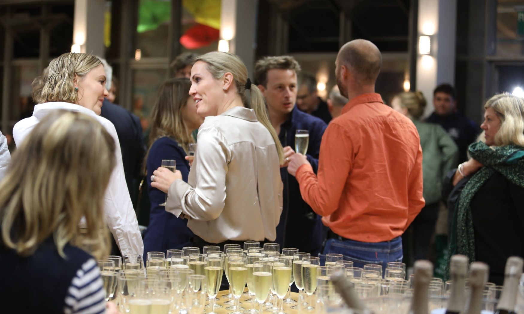 A group of people are standing around a table filled with champagne glasses.