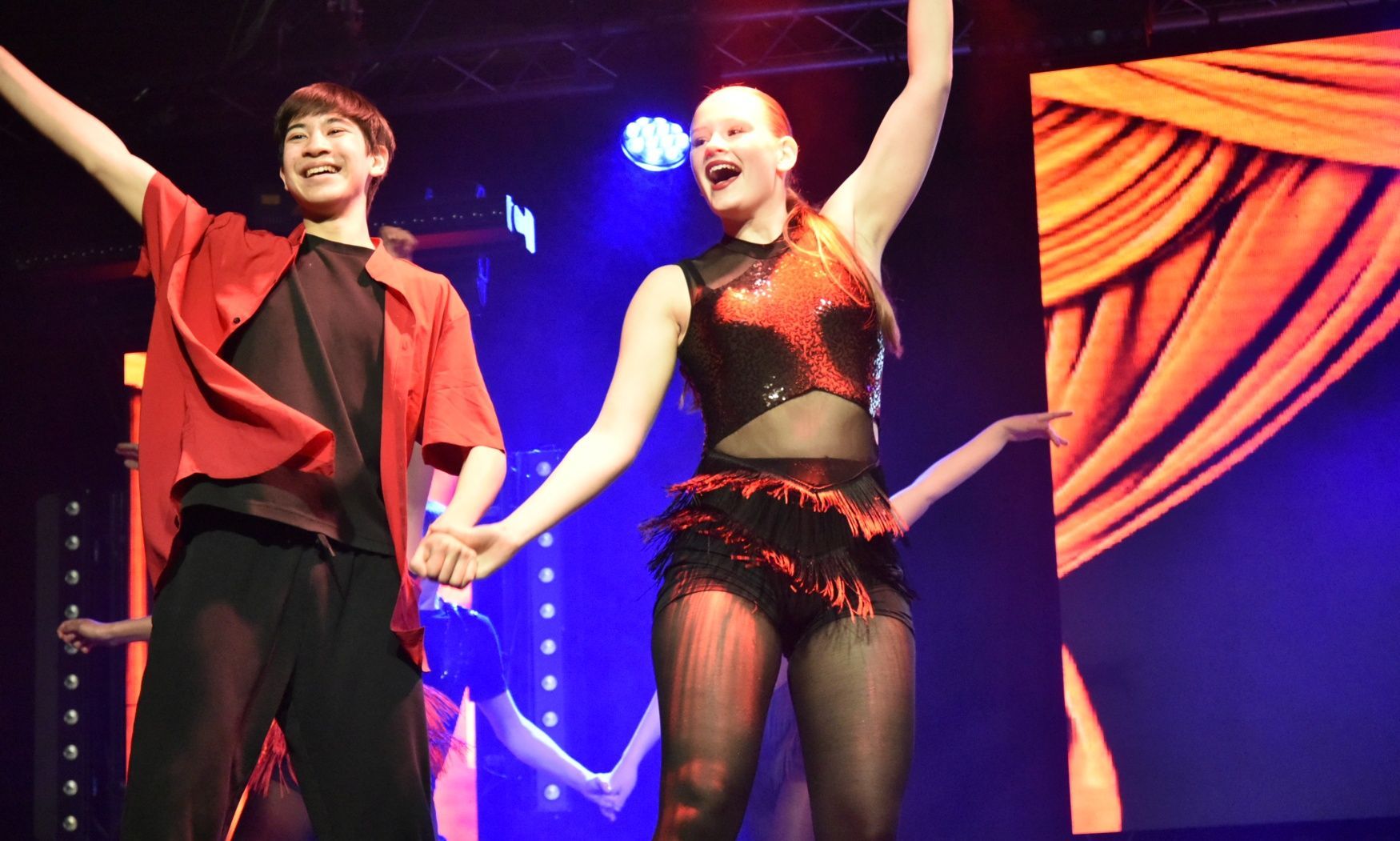 A man and a woman are holding hands on a stage.