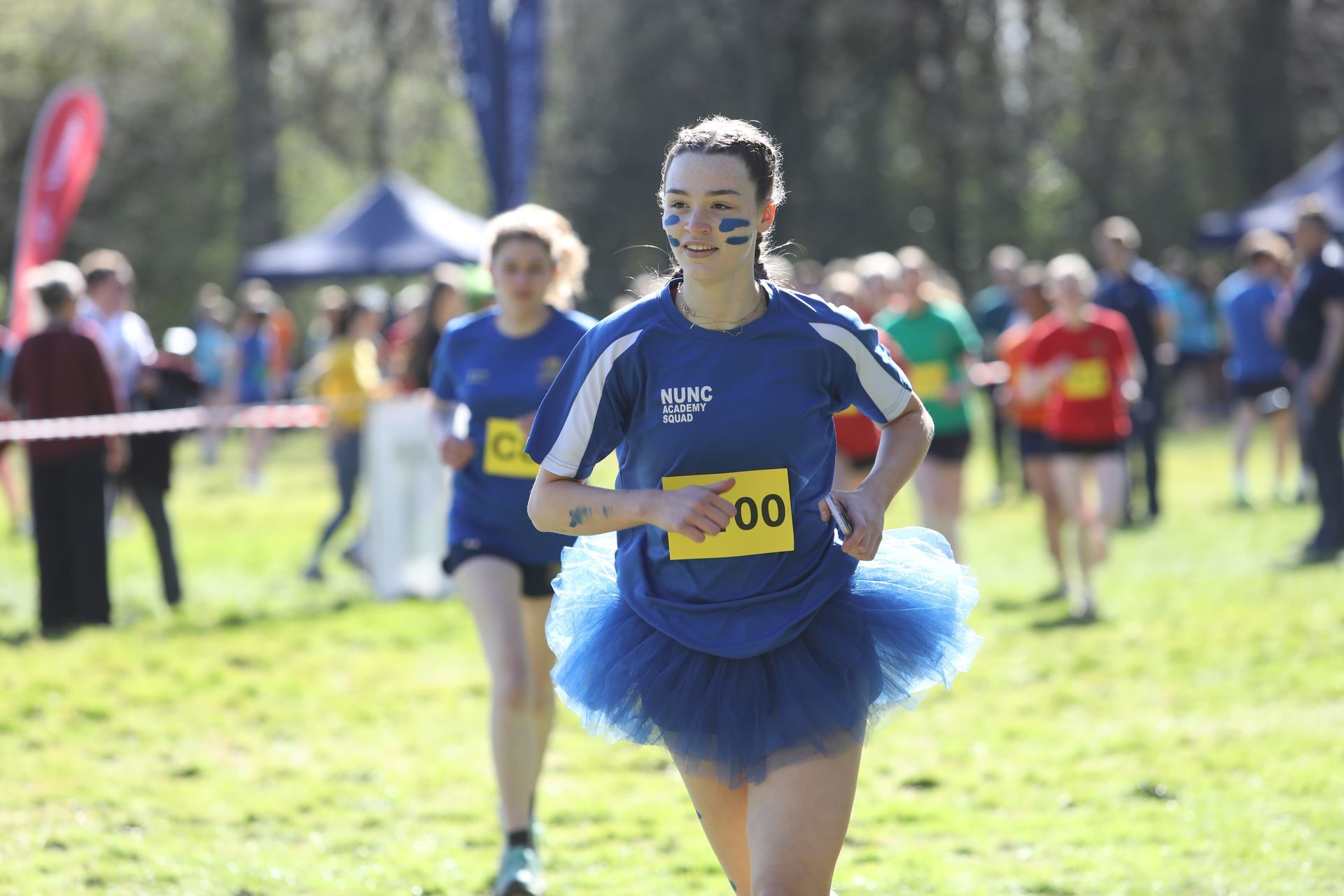A woman wearing a yellow shirt with the number 8121 on it is standing next to another woman.