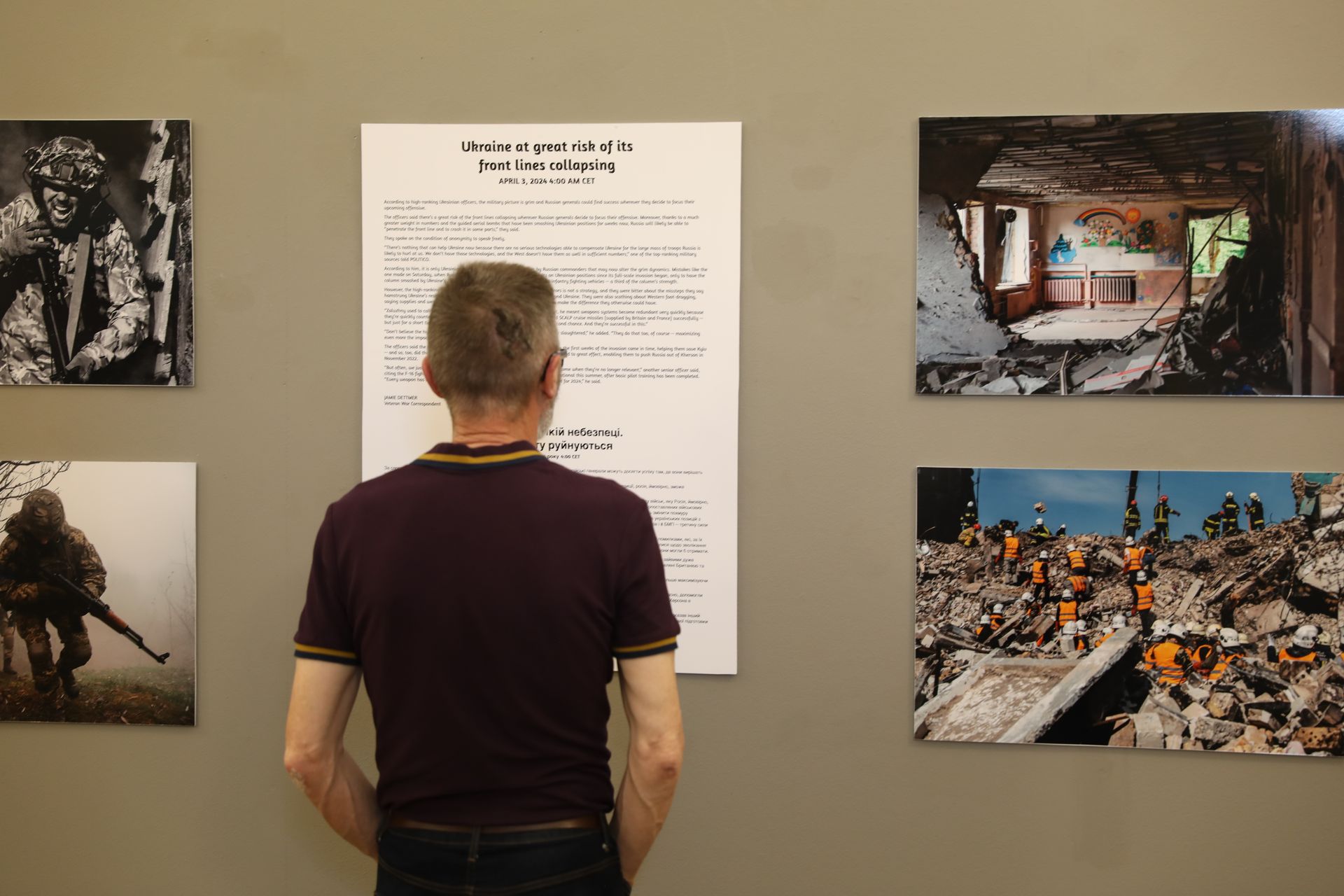 A man is looking at pictures on a wall in a museum.