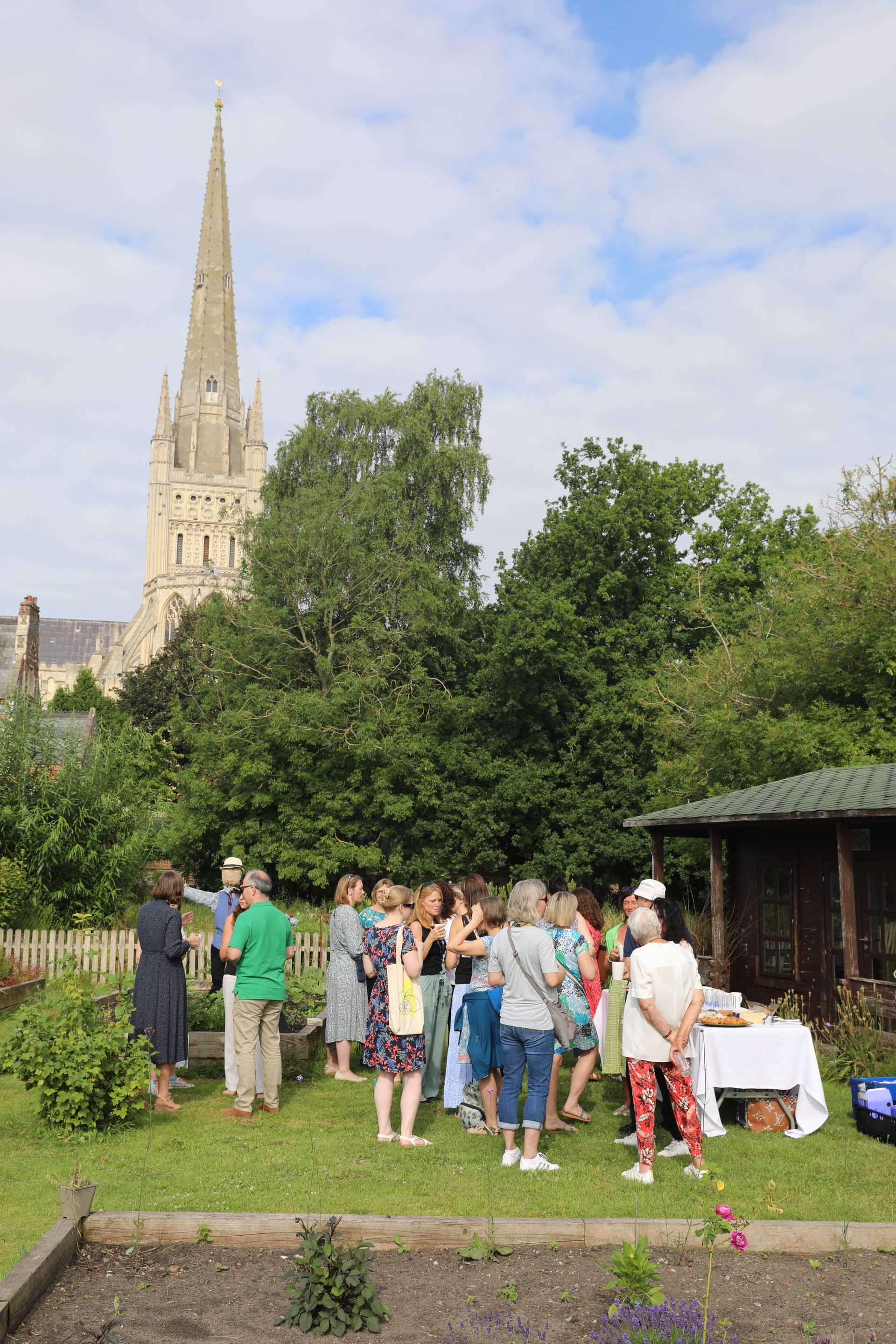 A round table with plates , utensils , and a vase of flowers on it.