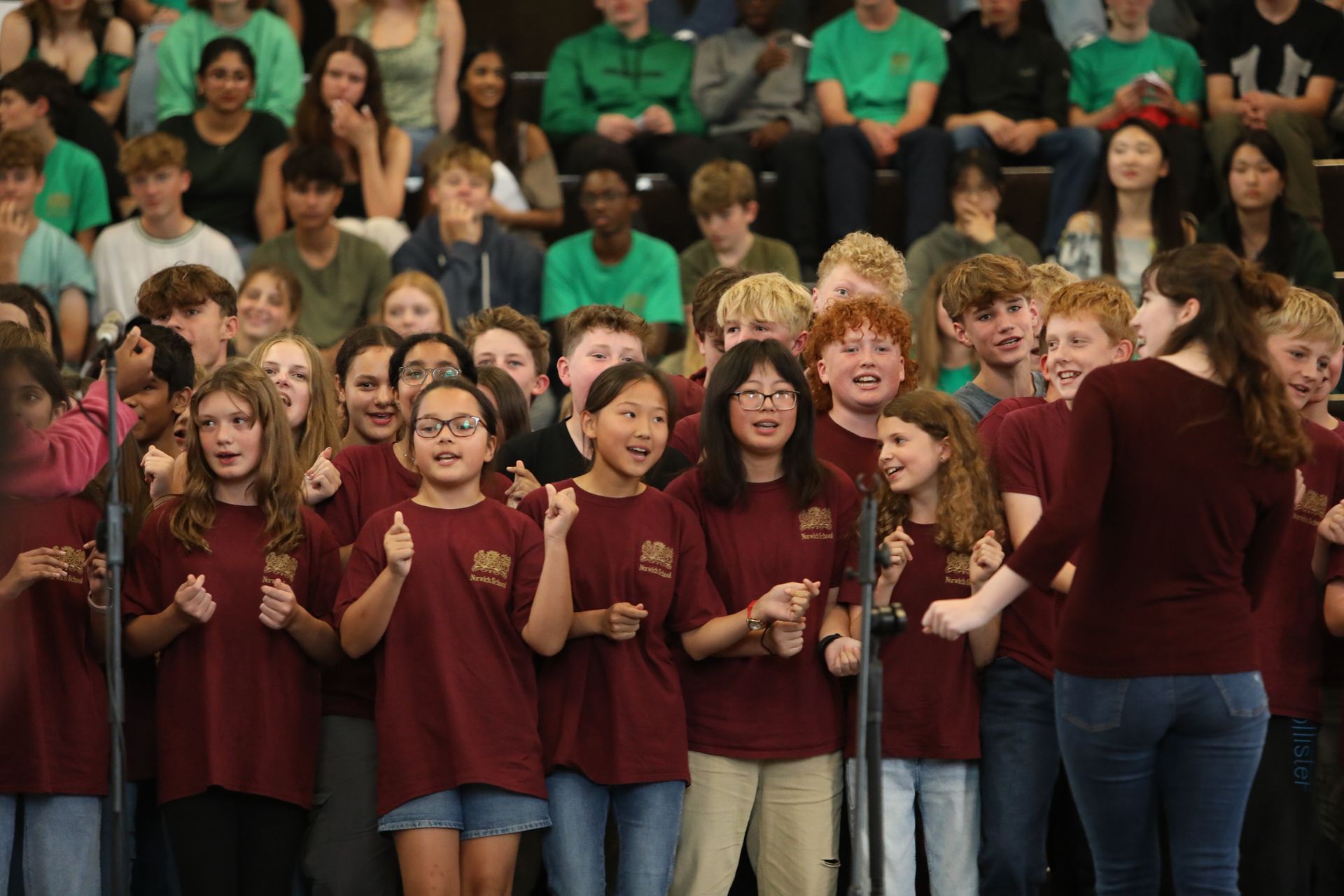 A group of young people are singing in front of a crowd.