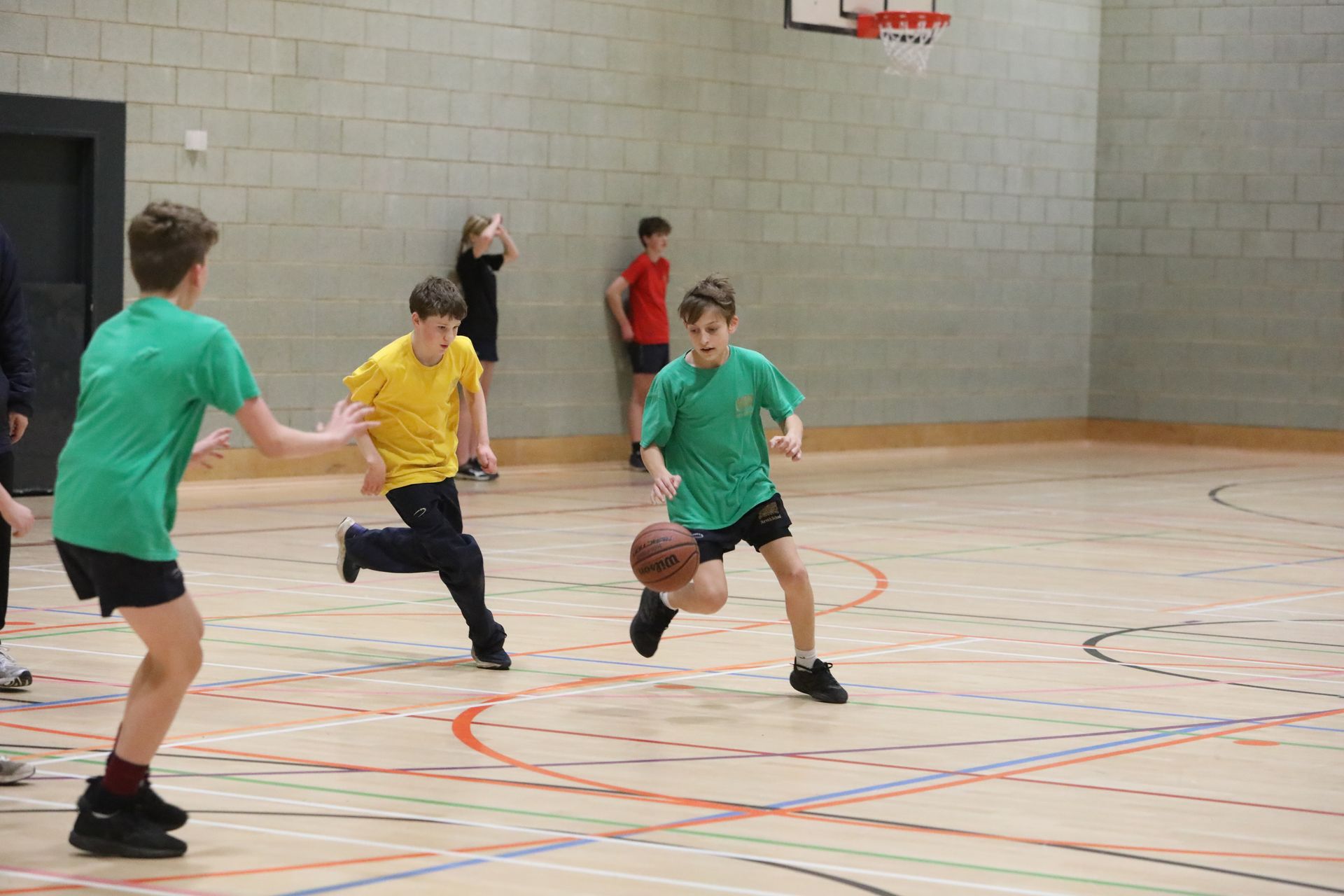 A group of young boys are playing basketball in a gym.