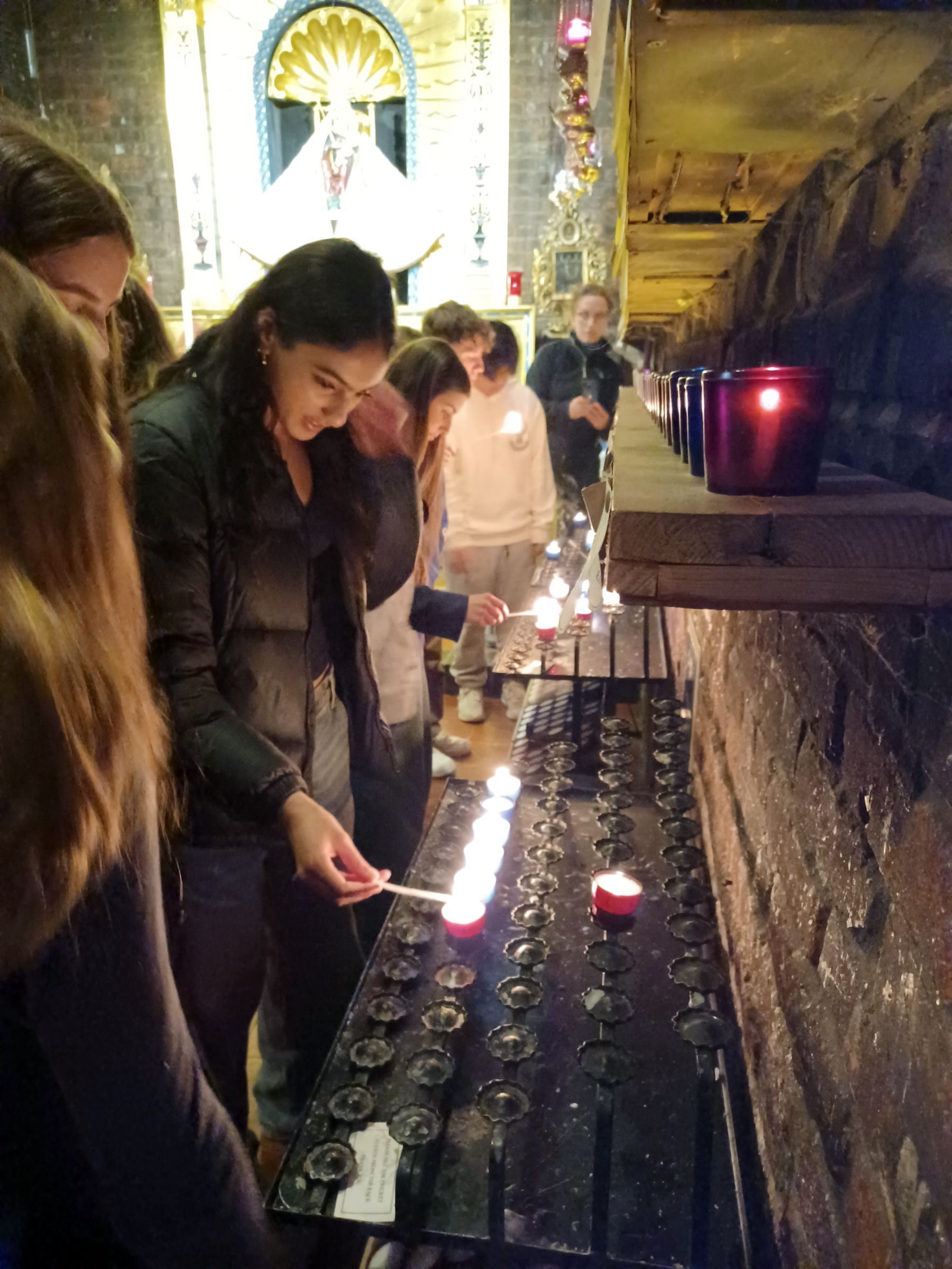 A group of people are lighting candles in a church.