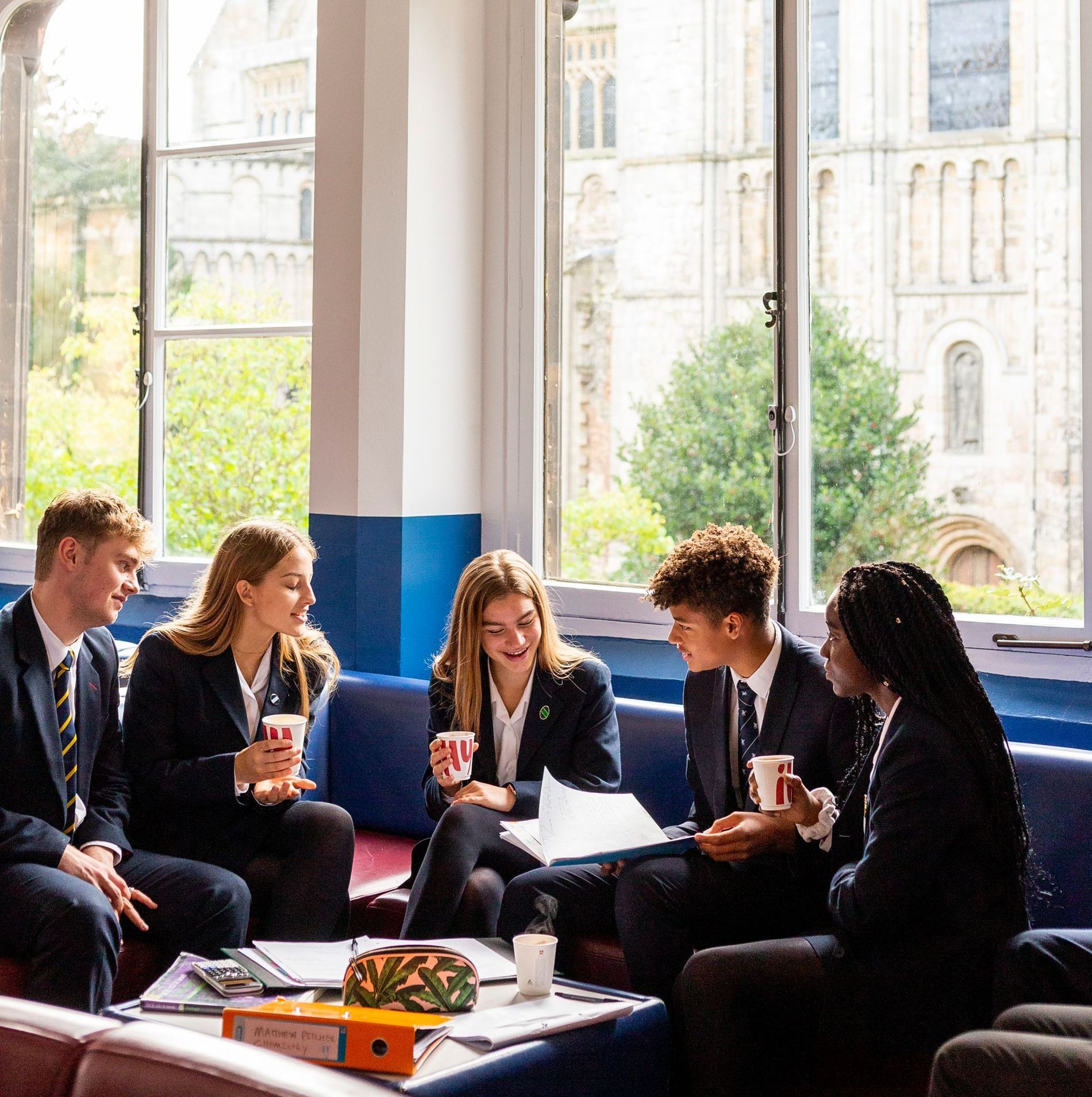 A group of people are sitting on a couch in front of a window.