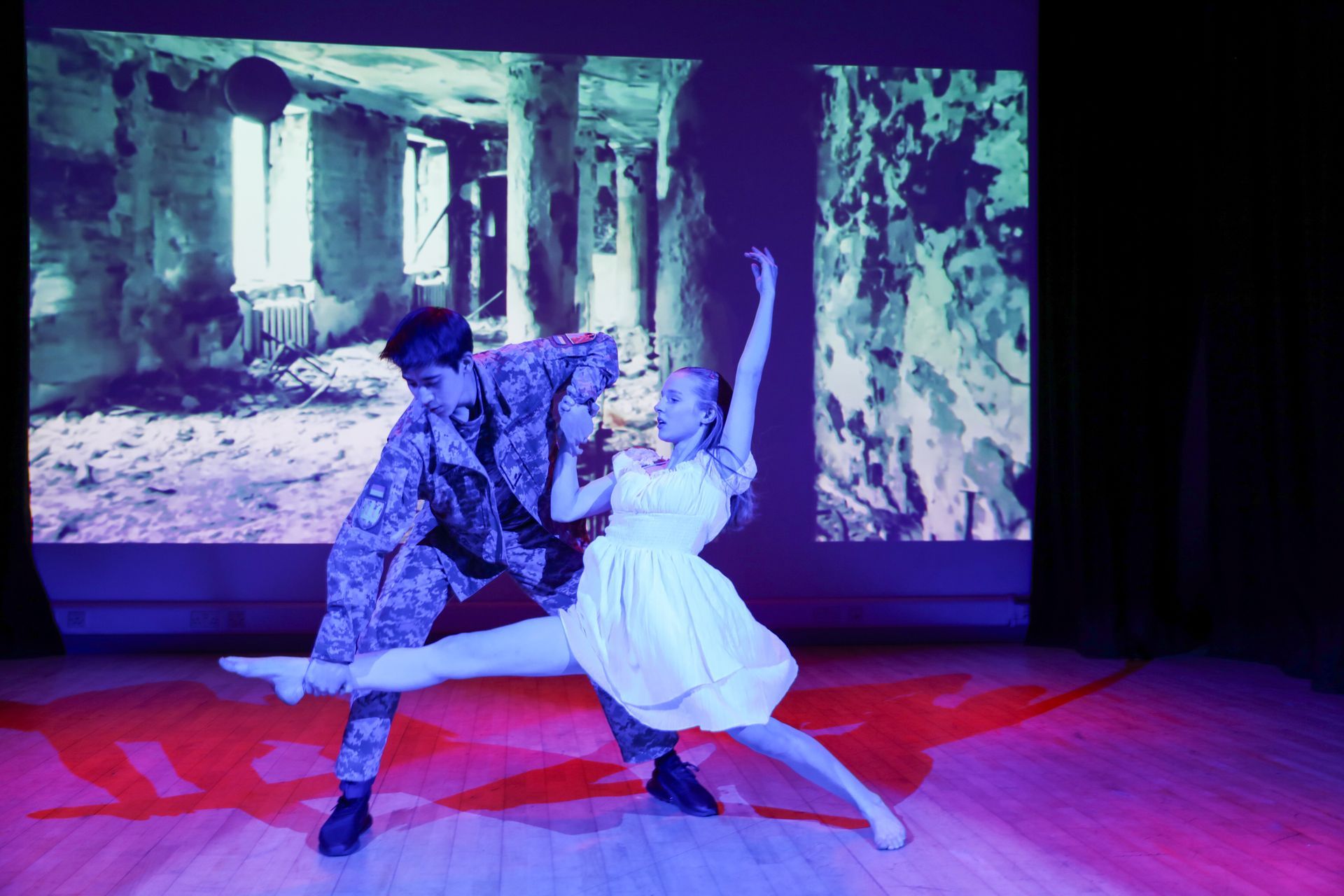 A group of children are standing on a stage with their hands in the air.