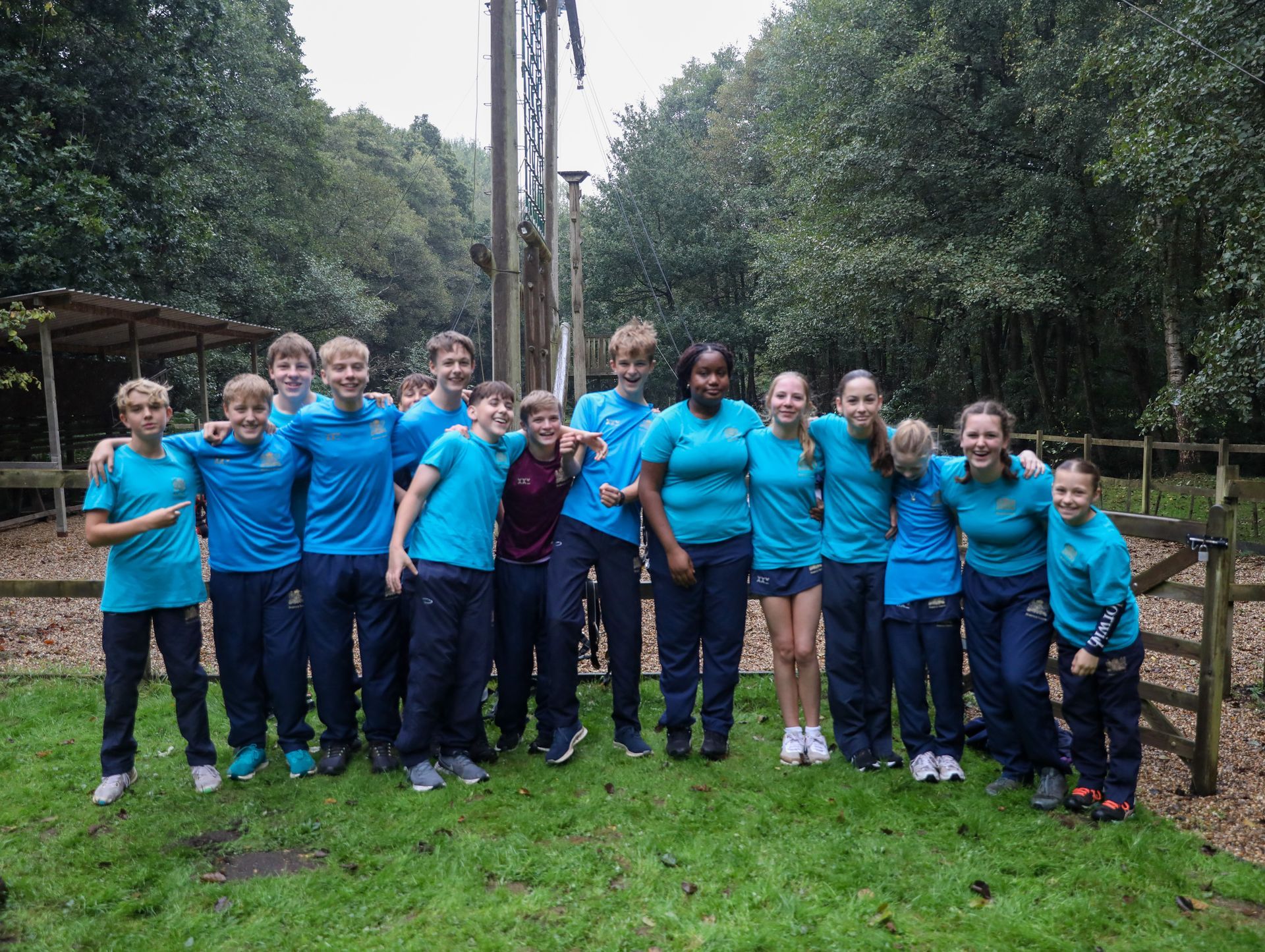 A group of boys in blue shirts are singing in front of a microphone