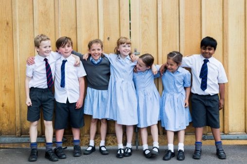 A group of children in school uniforms are posing for a picture.