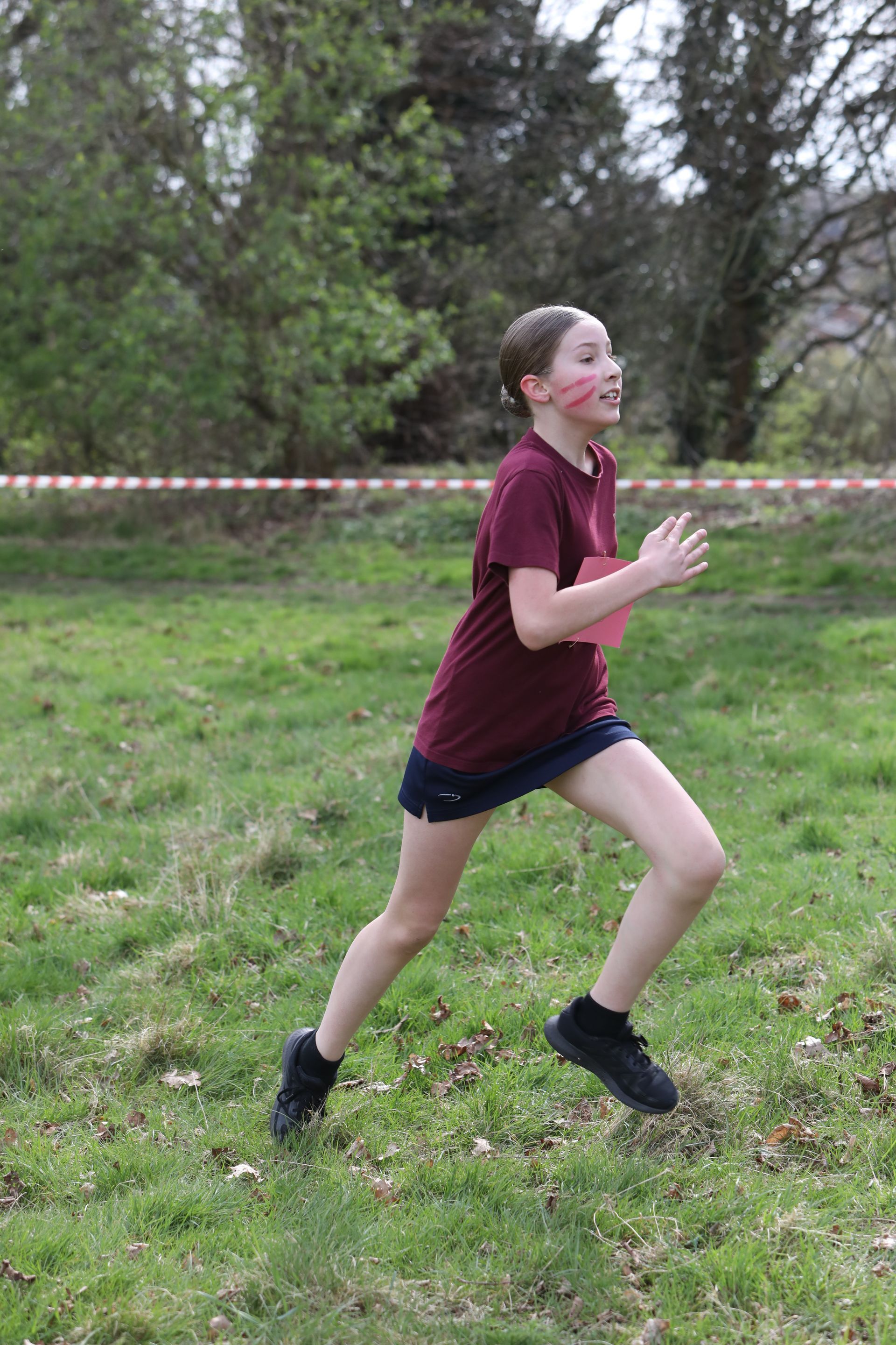 A young girl with red paint on her face is running in a field.