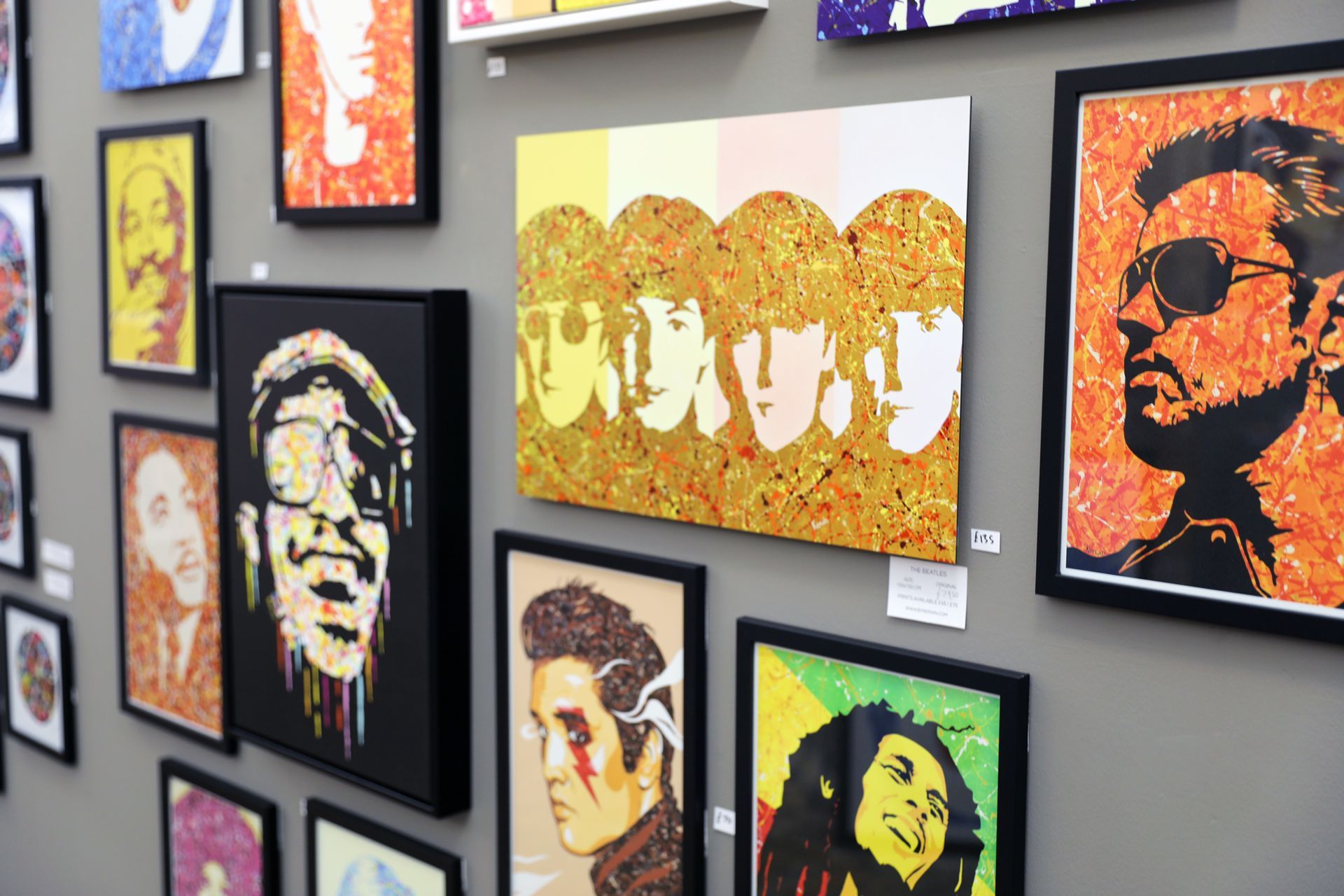 A wall with a bunch of paintings on it one of which has the word ubuy on it