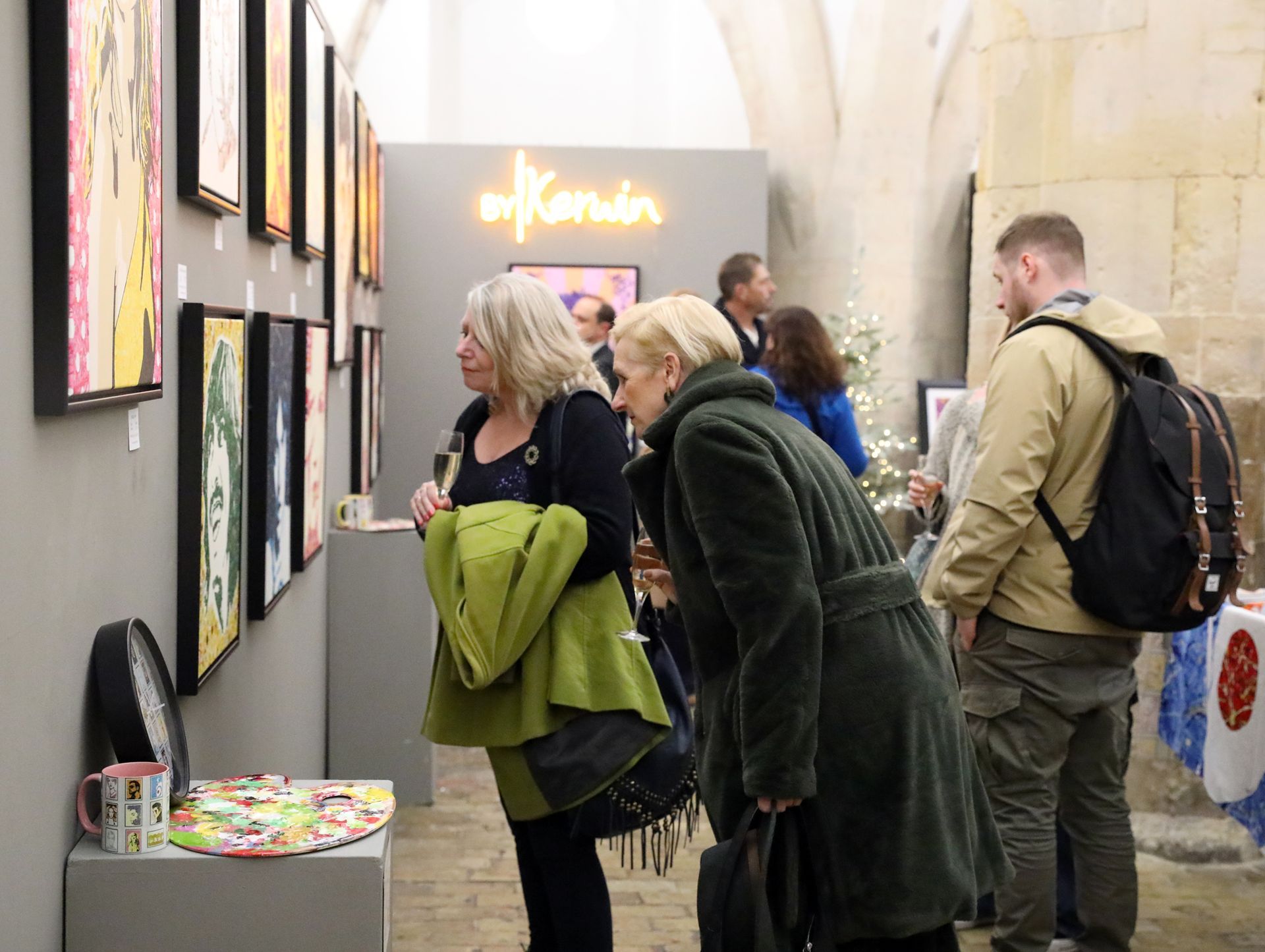 A group of people are looking at paintings in an art gallery.